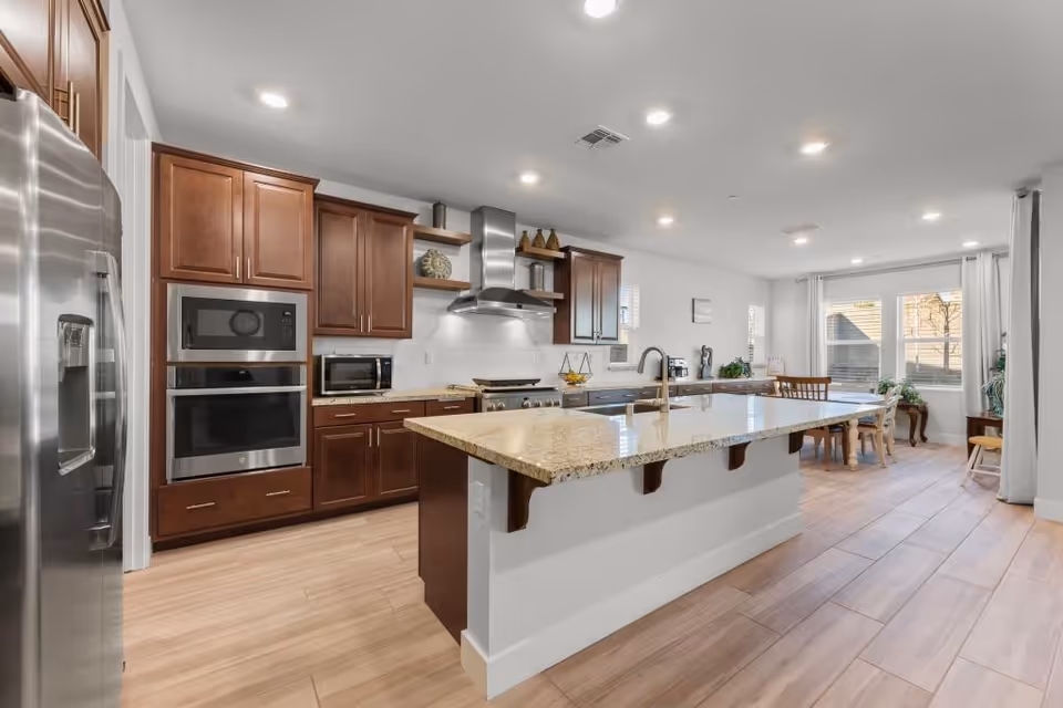 Open concept kitchen with granite island, dark wood cabinets, and dining area.