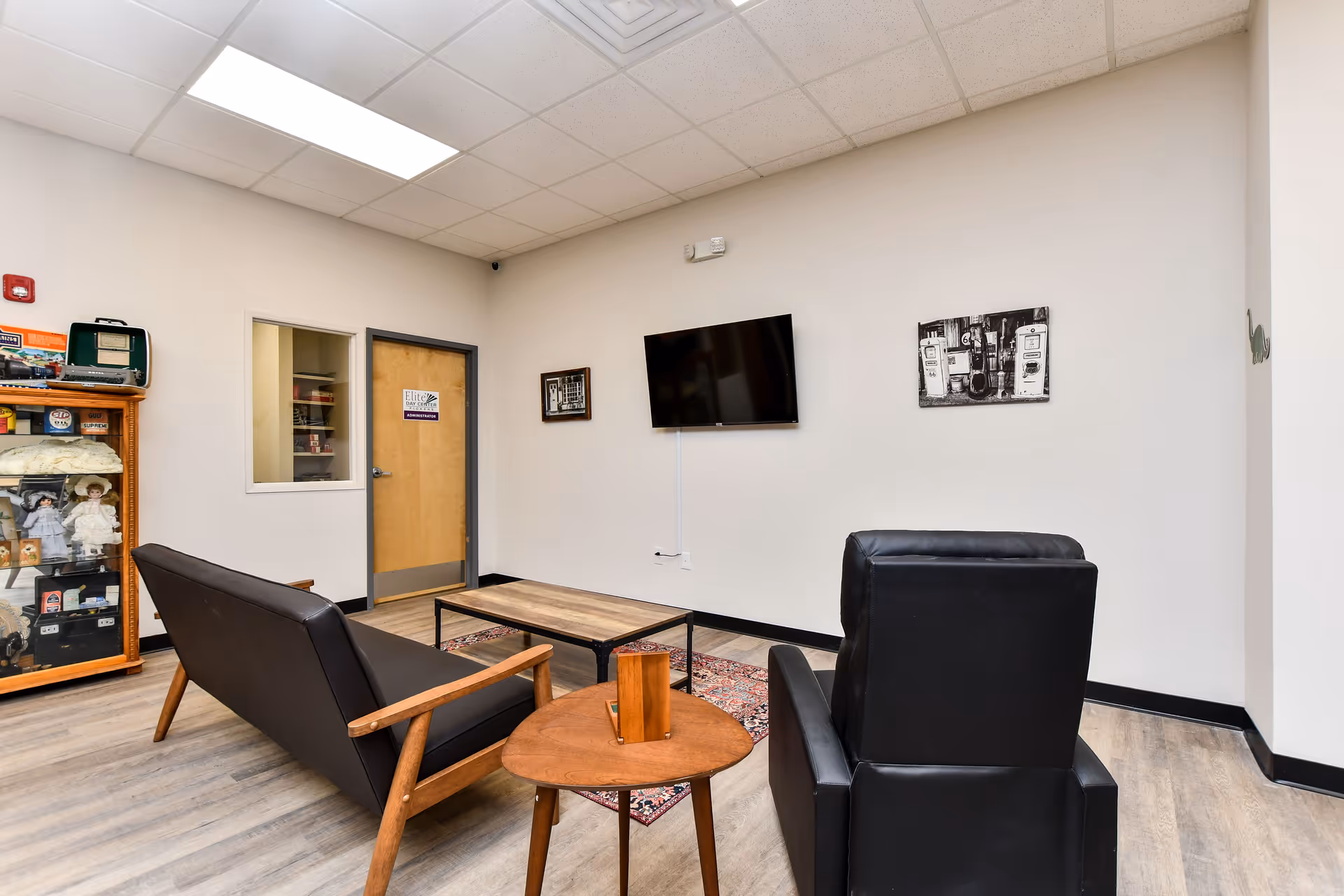 A small lobby lounge with black leather chairs, a sofa, coffee table, and wall TV.