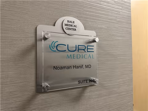 Metal plaque on textured wall shows Cure Medical and Noaman Hanif, MD.