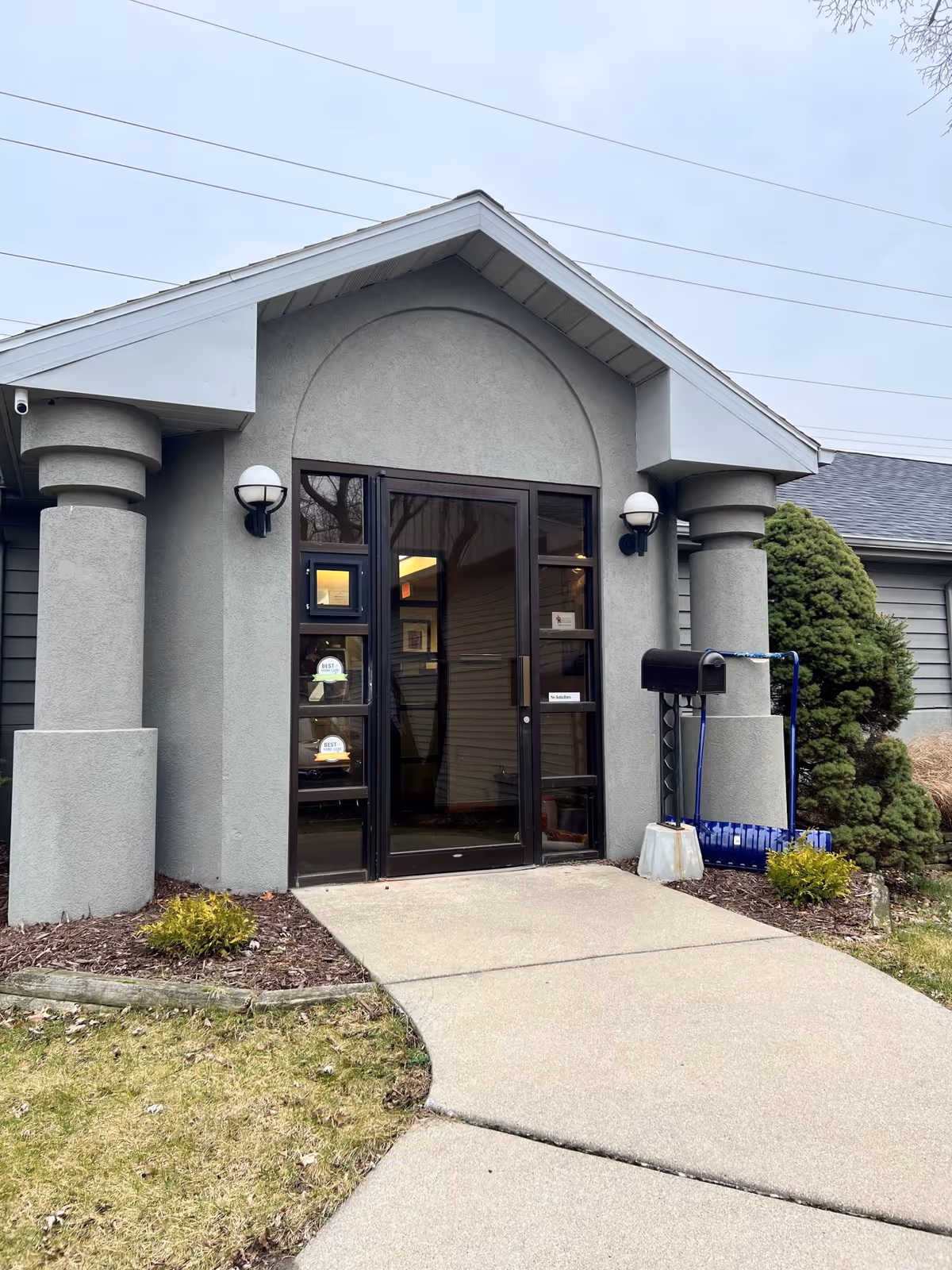 Entrance to Home Instead senior living facility with glass doors and concrete pillars.