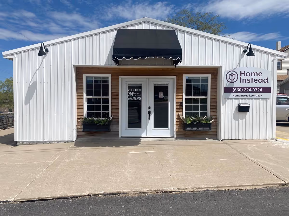 White storefront with double doors, black awning, and a Home Instead sign.