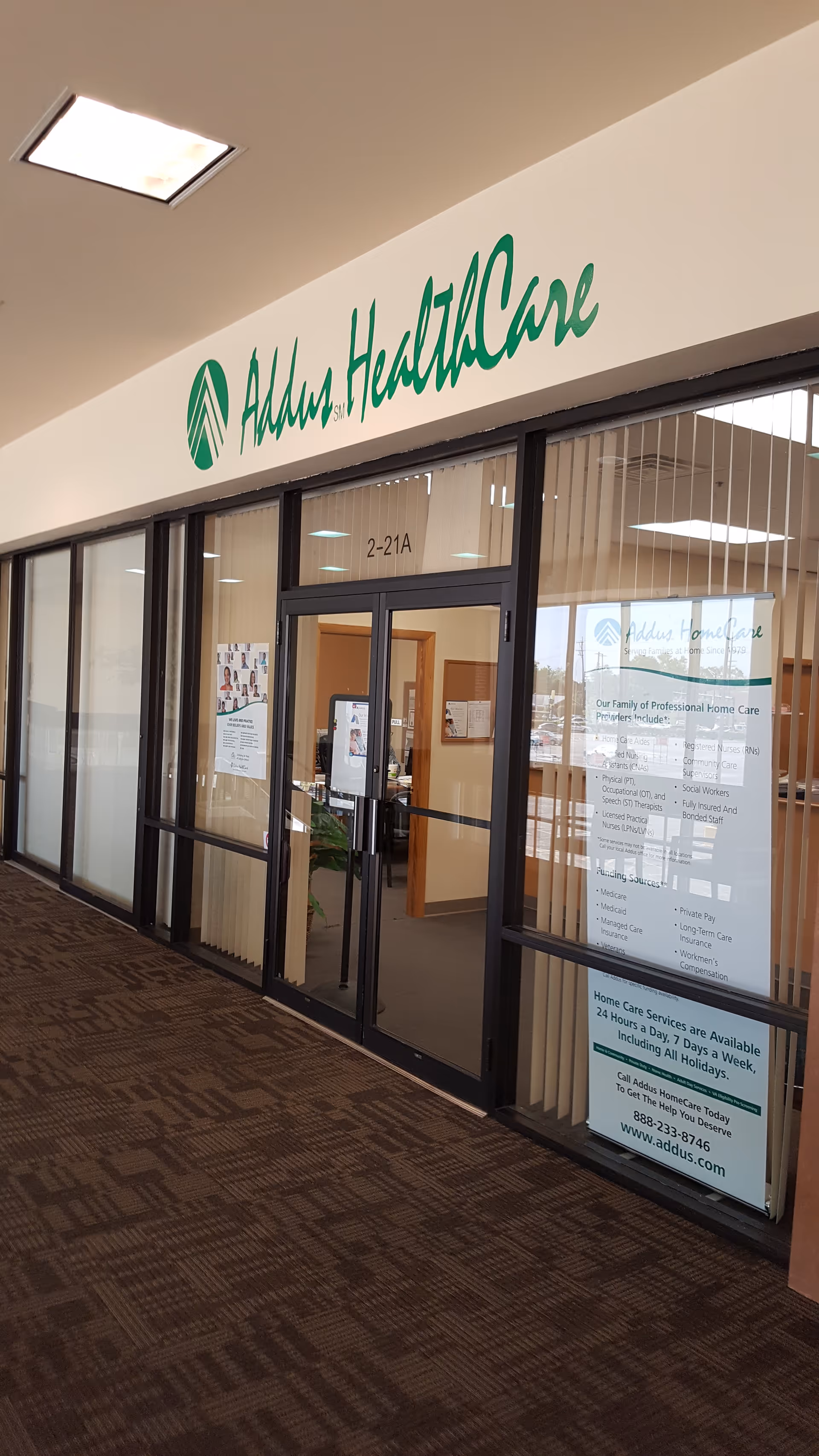 Entrance to Addus HomeCare through glass doors in a mall corridor.