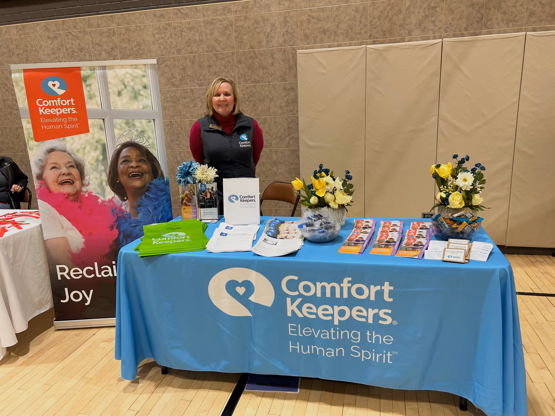 Indoor Comfort Keepers booth featuring a blue tablecloth and staff member.