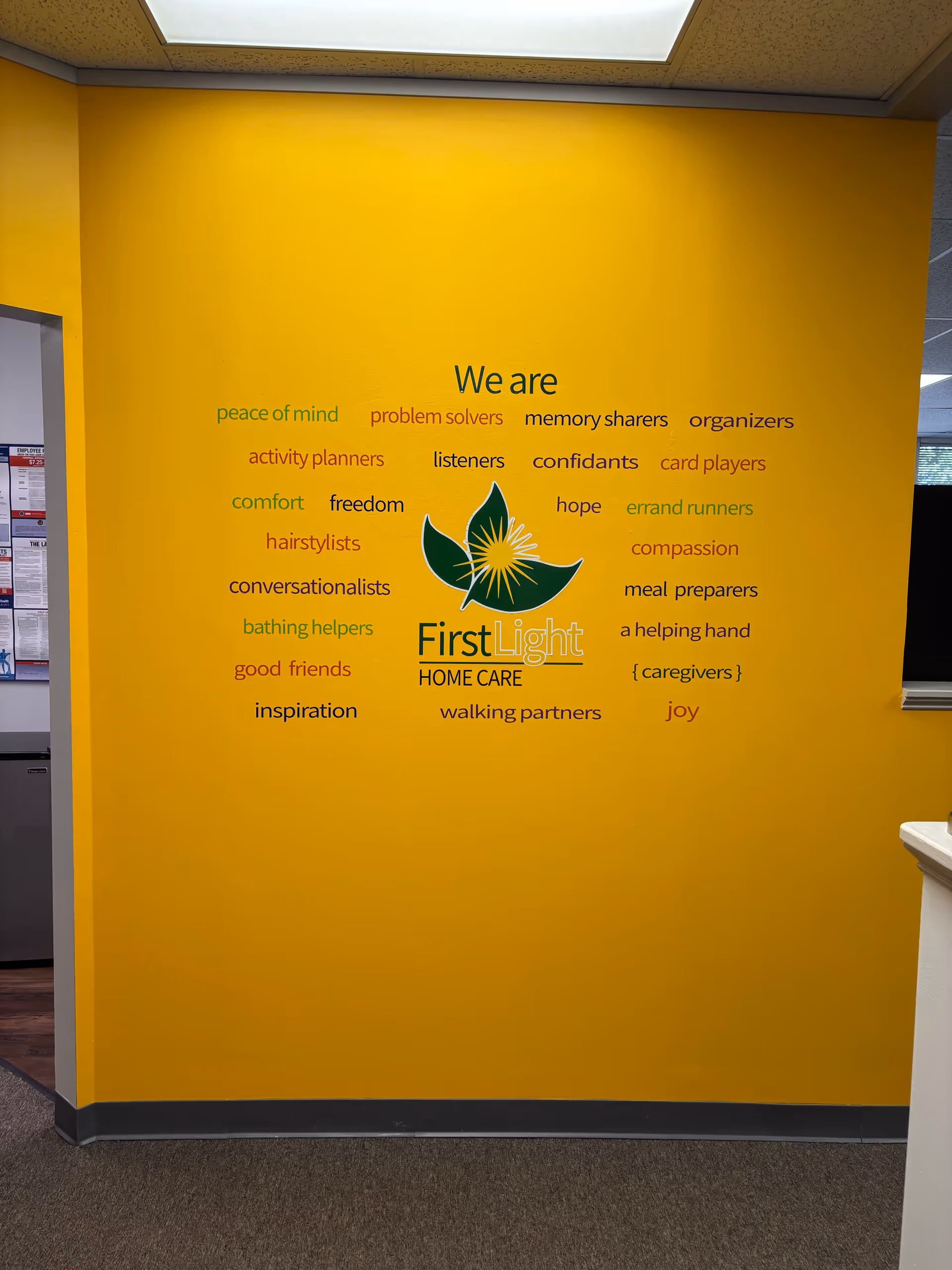 Bright yellow interior wall featuring We are text and FirstLight Home Care logo.
