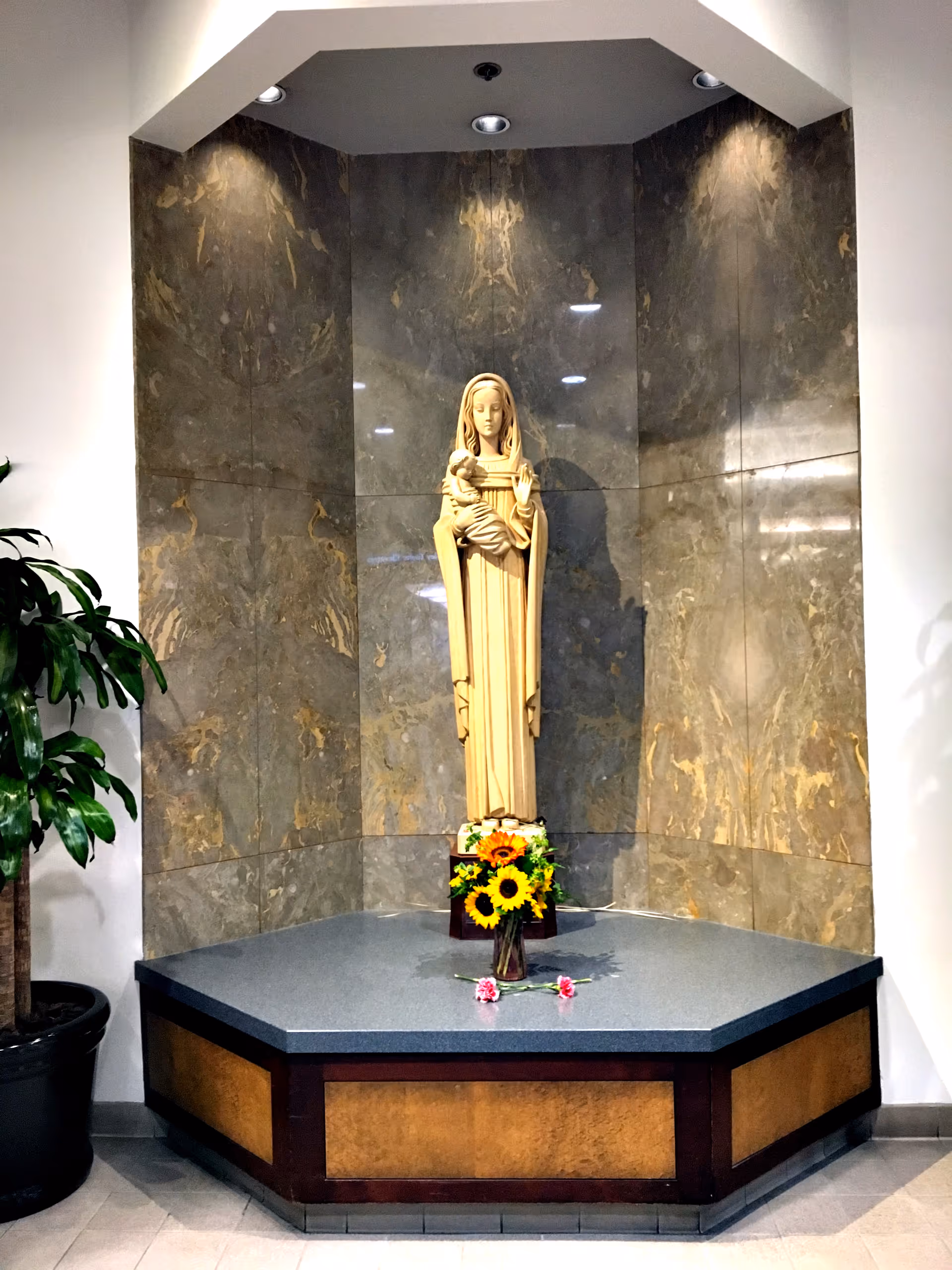 Statue of a veiled woman holding a child in a marble alcove.