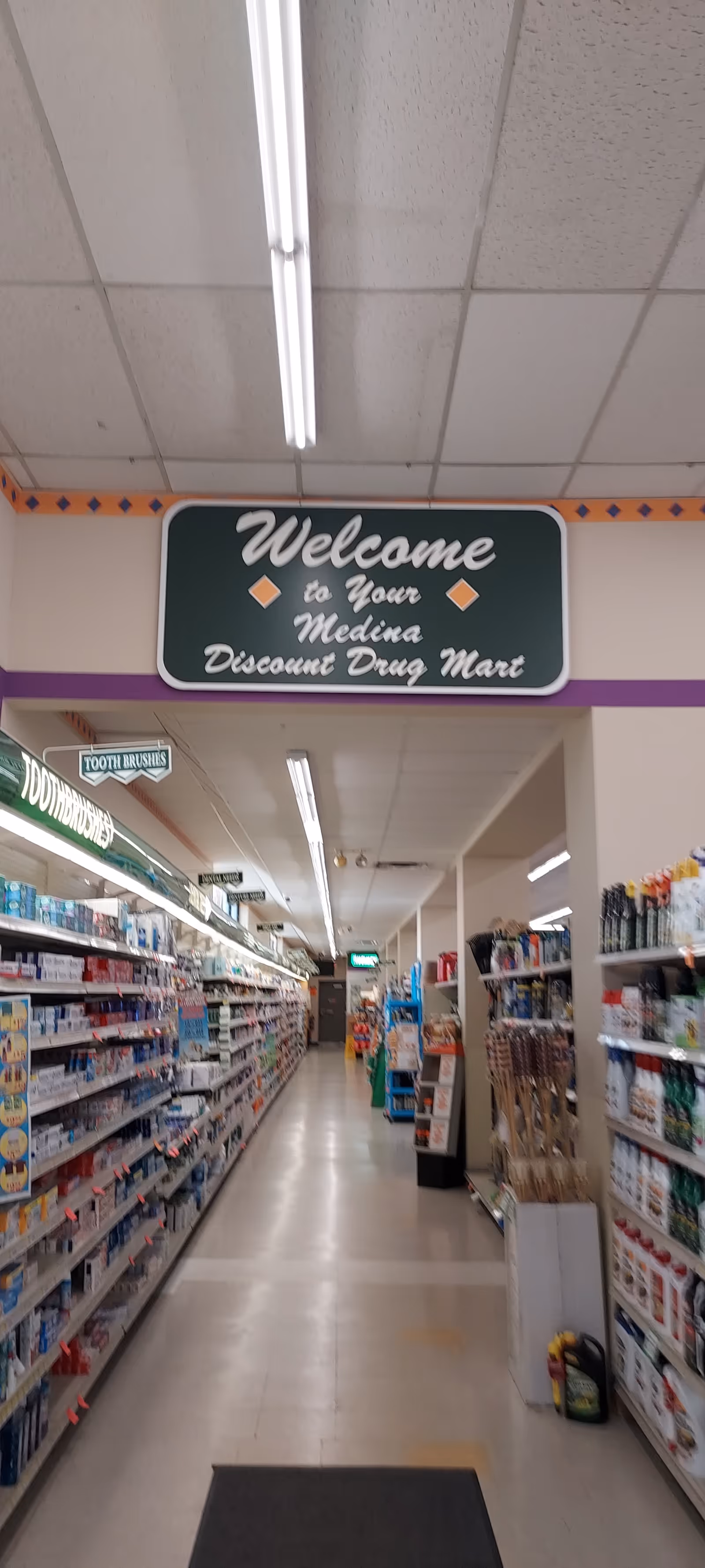 Interior view of Discount Drug Mart with long aisles, fluorescent lighting, and shelves stocked with products.