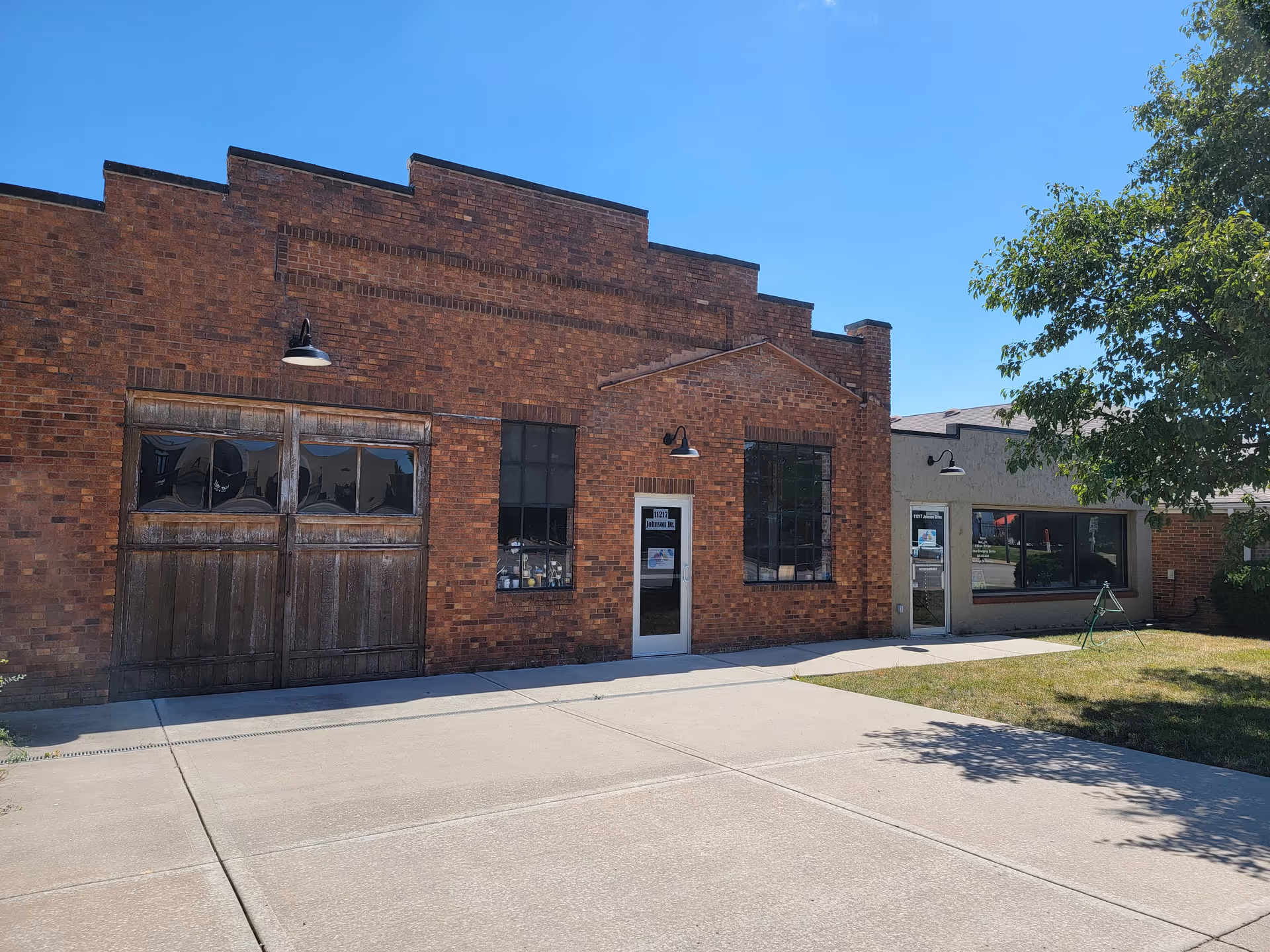 Brick facility front with door, large windows, and a sidewalk under blue sky.