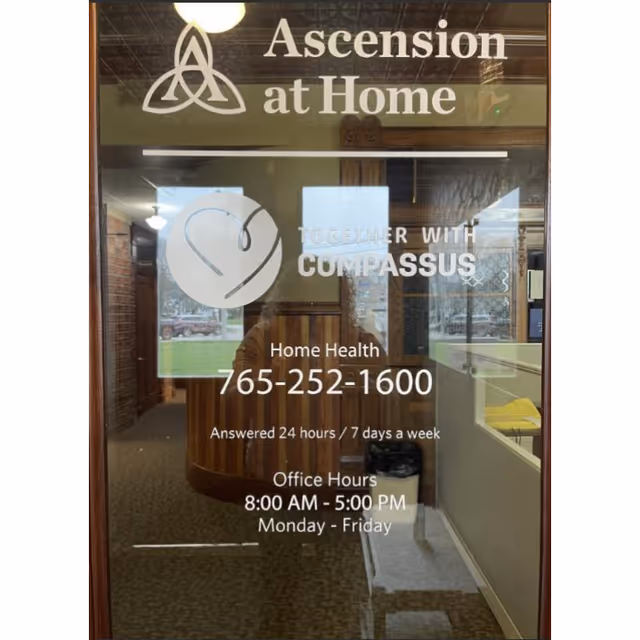 Glass entrance door with Ascension at Home and Compassus branding and office hours.