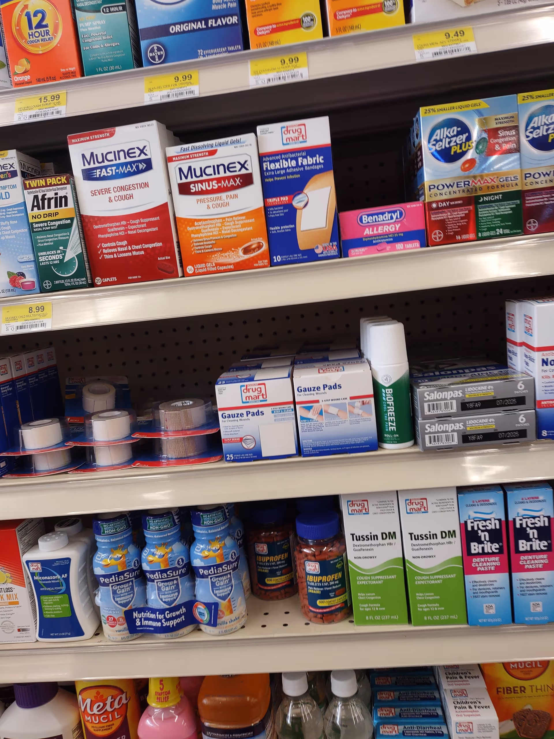 Store shelves at Discount Drug Mart stocked with cold medications, gauze pads, and dental care products.