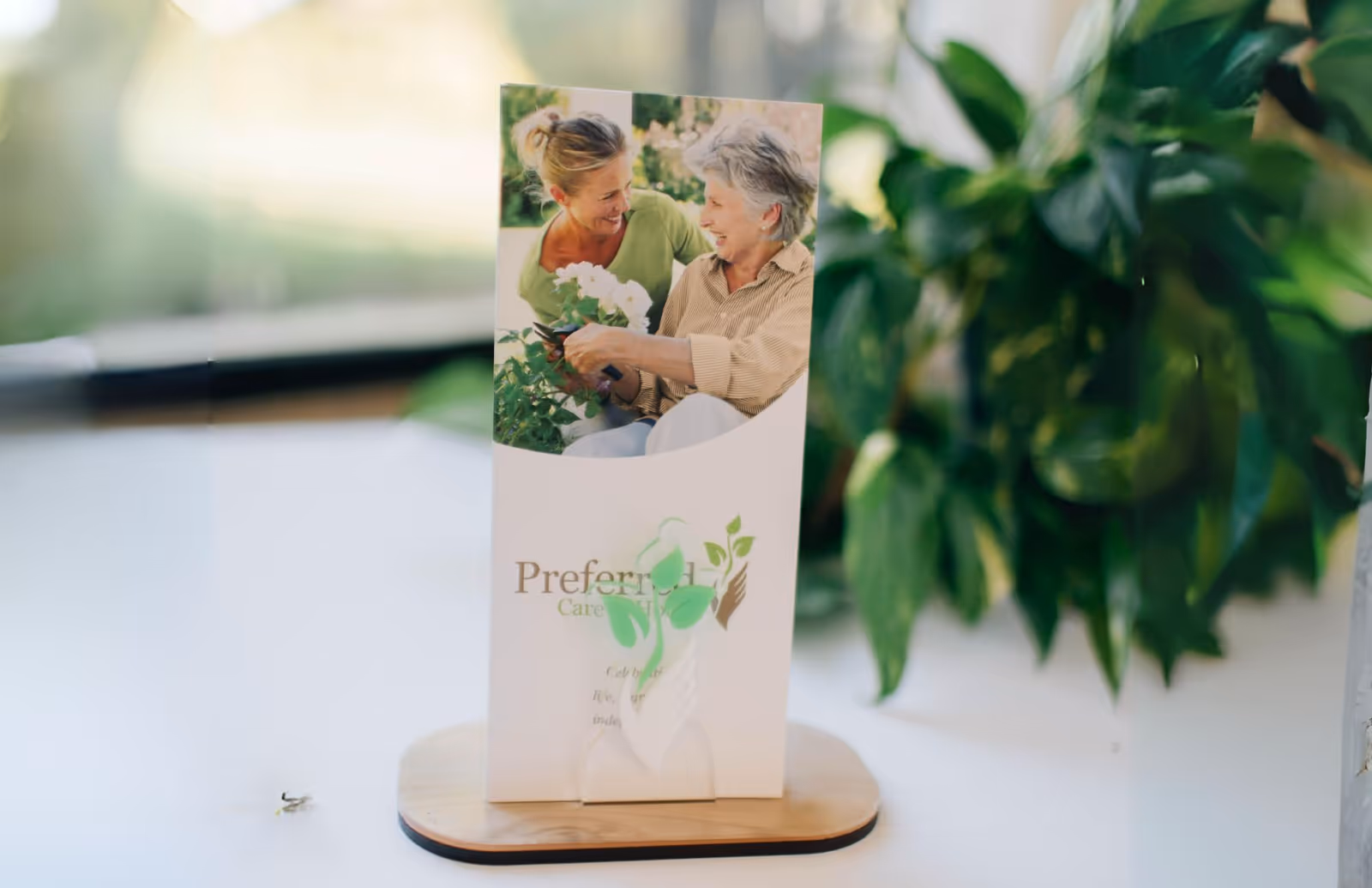 Promotional brochure for Preferred Care at Home sits on a table with green plants nearby.