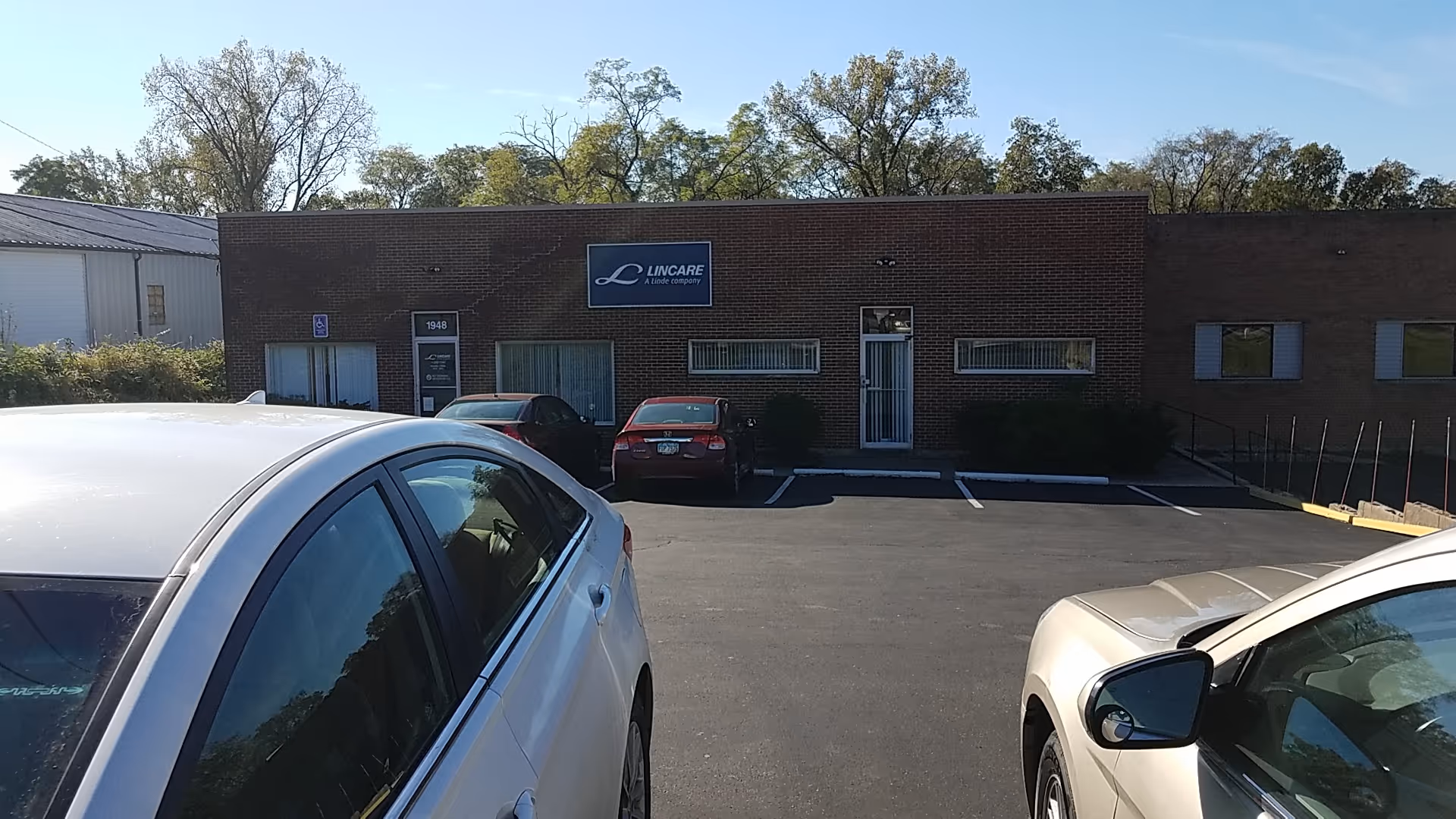 Exterior view of a LINCARE senior living facility front with parked cars