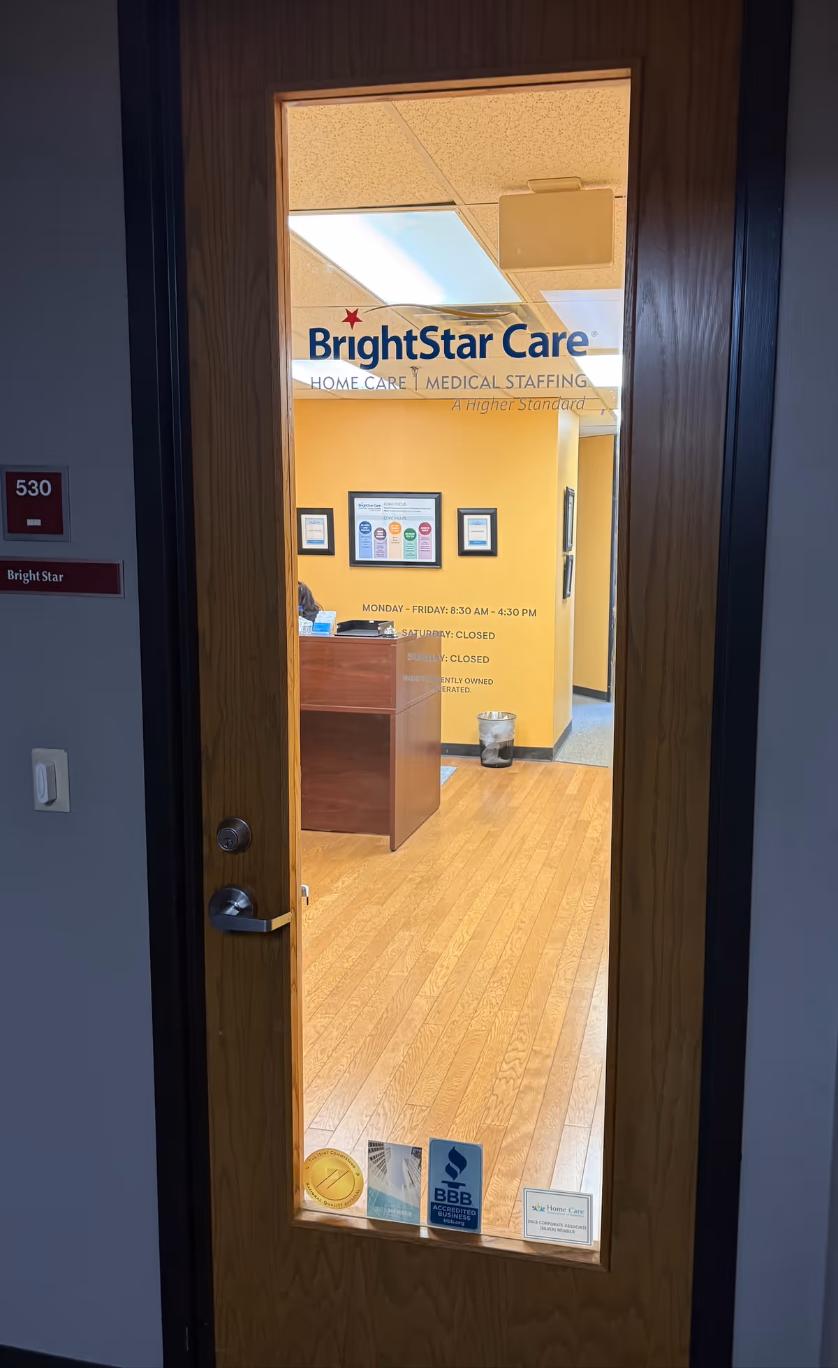 Interior view through a glass door of BrightStar Care reception area with yellow walls.