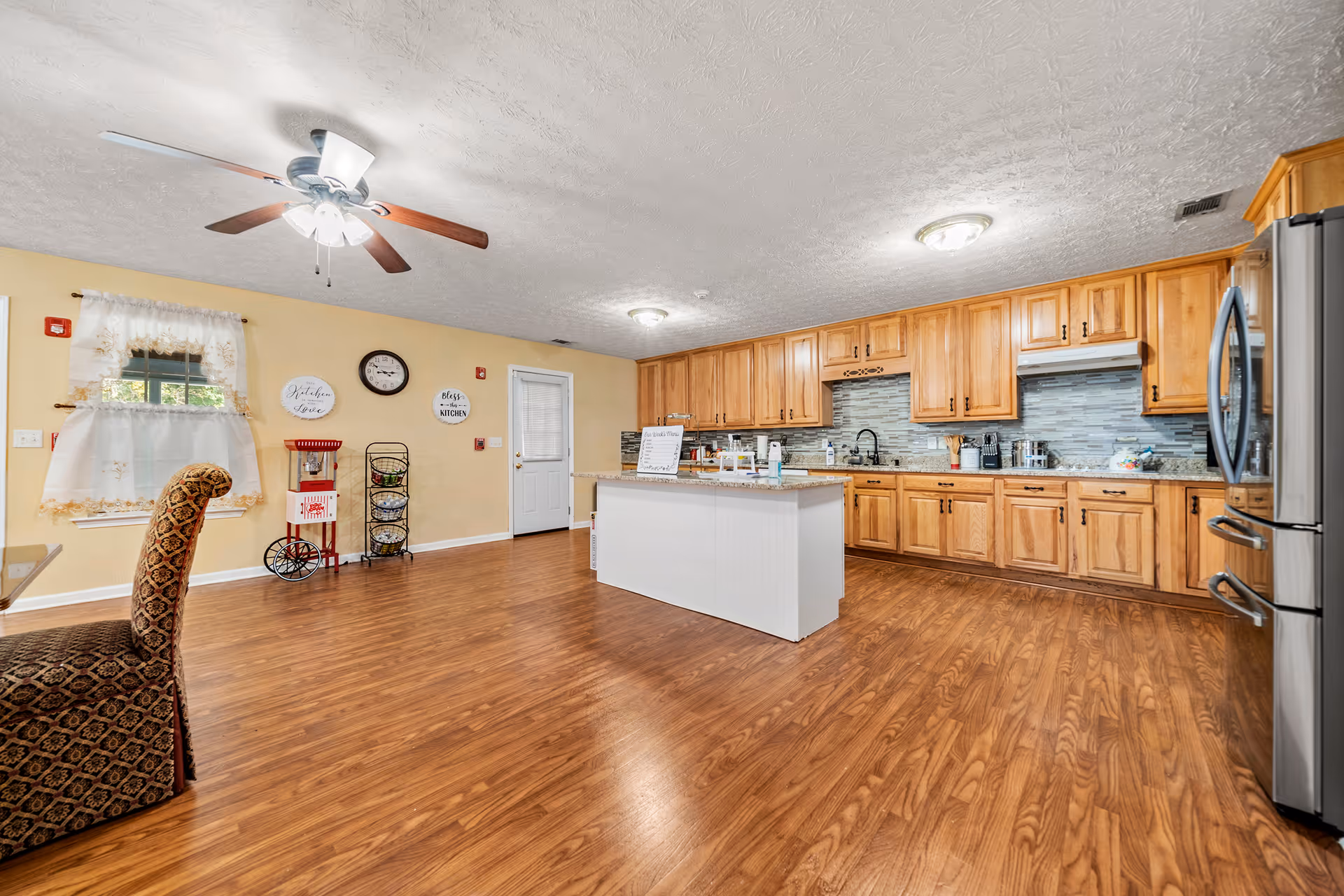 Bright indoor kitchen in a senior living facility with an island and wooden cabinetry.