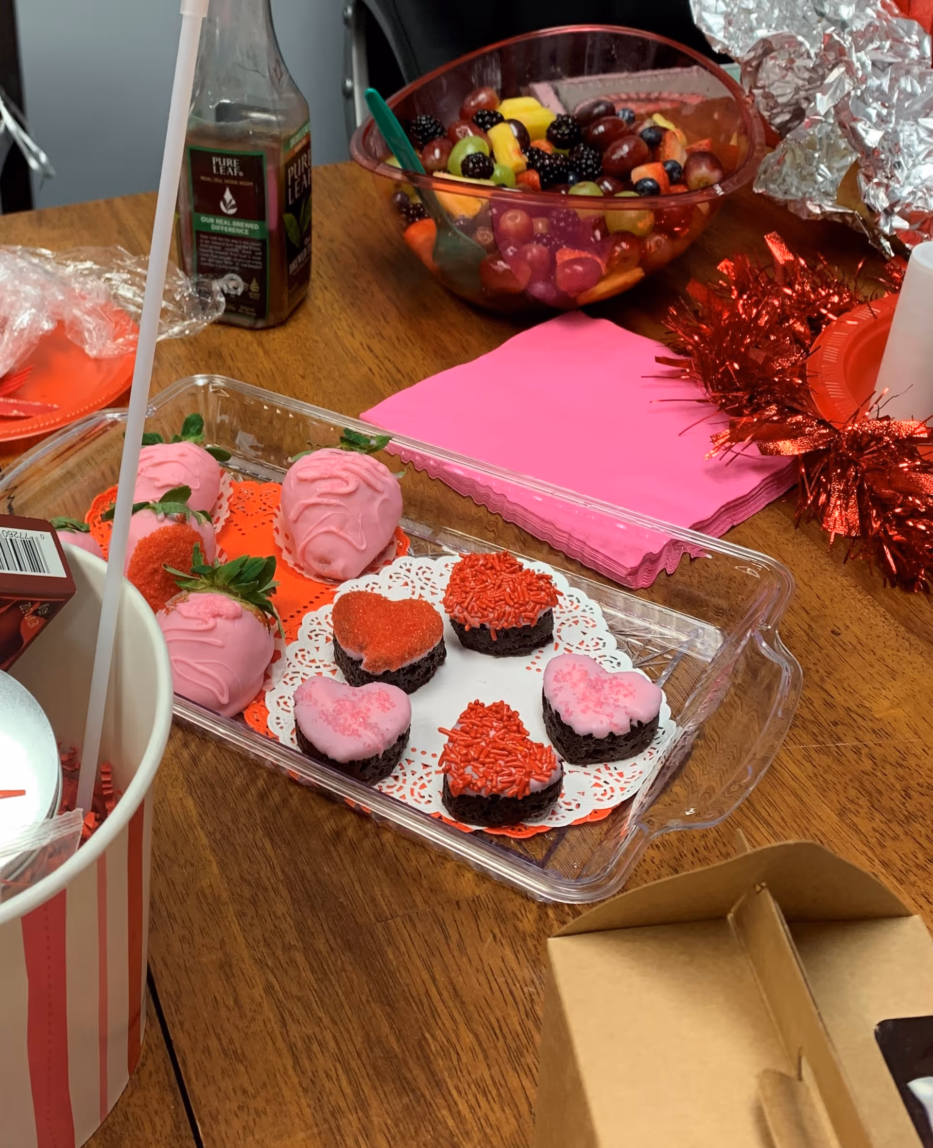 Dessert tray with pink cupcakes and heart-shaped treats on a decorated table.