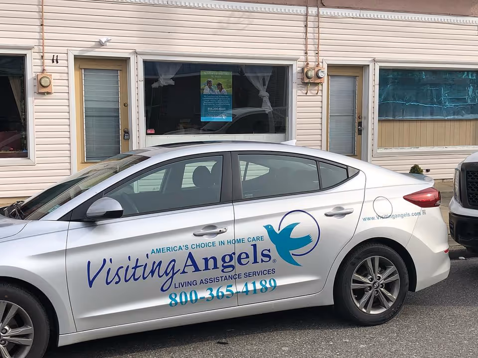 A Visiting Angels branded car parked in front of a senior care facility.