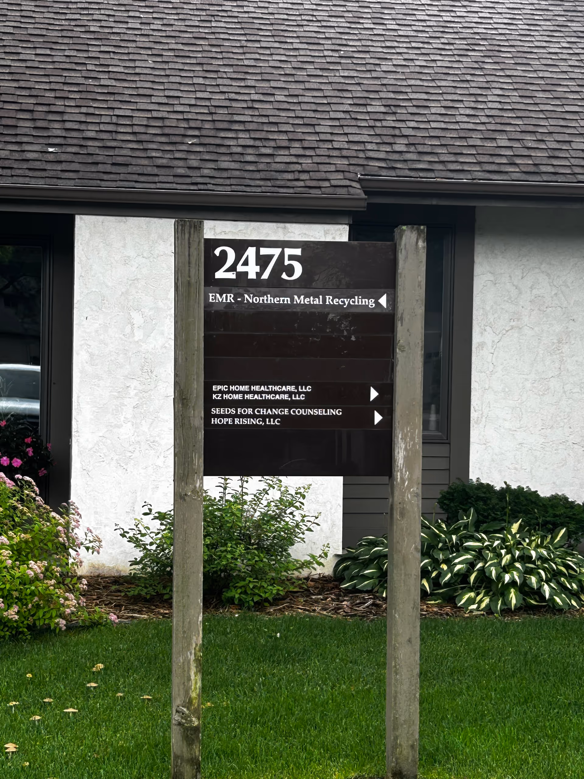 Front exterior of a building with a tall sign displaying 2475 and several business names.