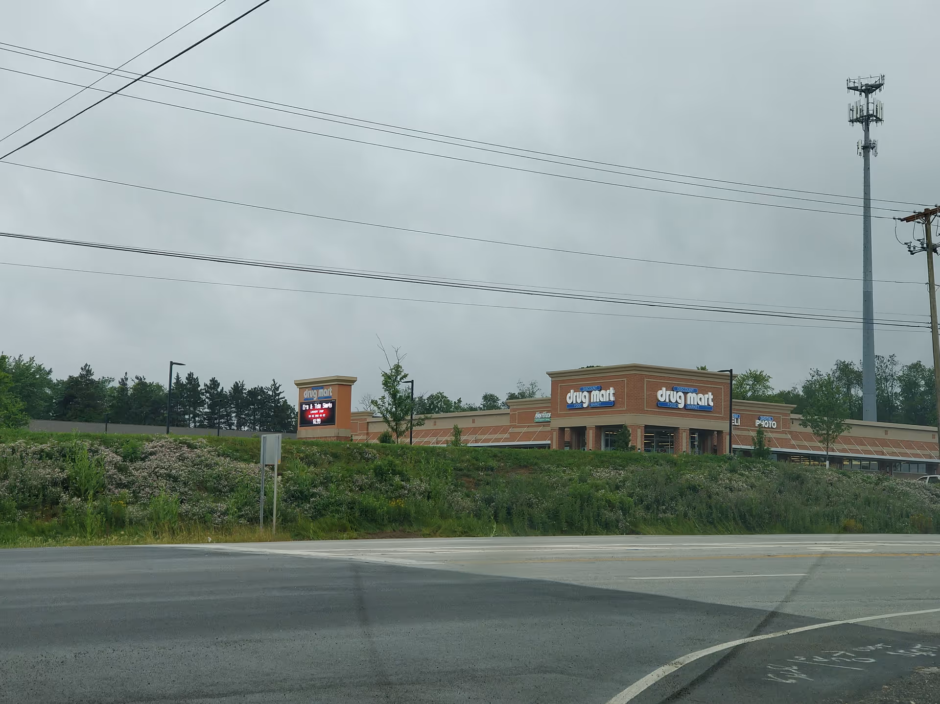 Exterior view of a Discount Drug Mart storefront along a road with power lines overhead