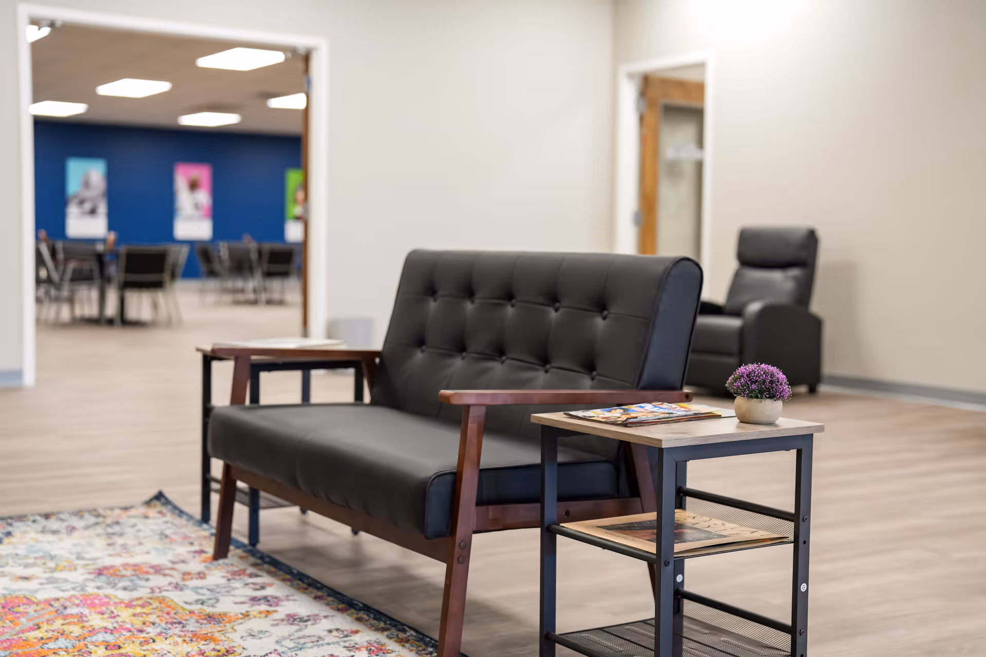Modern senior living lounge with black leather seating, a side table, and magazines.