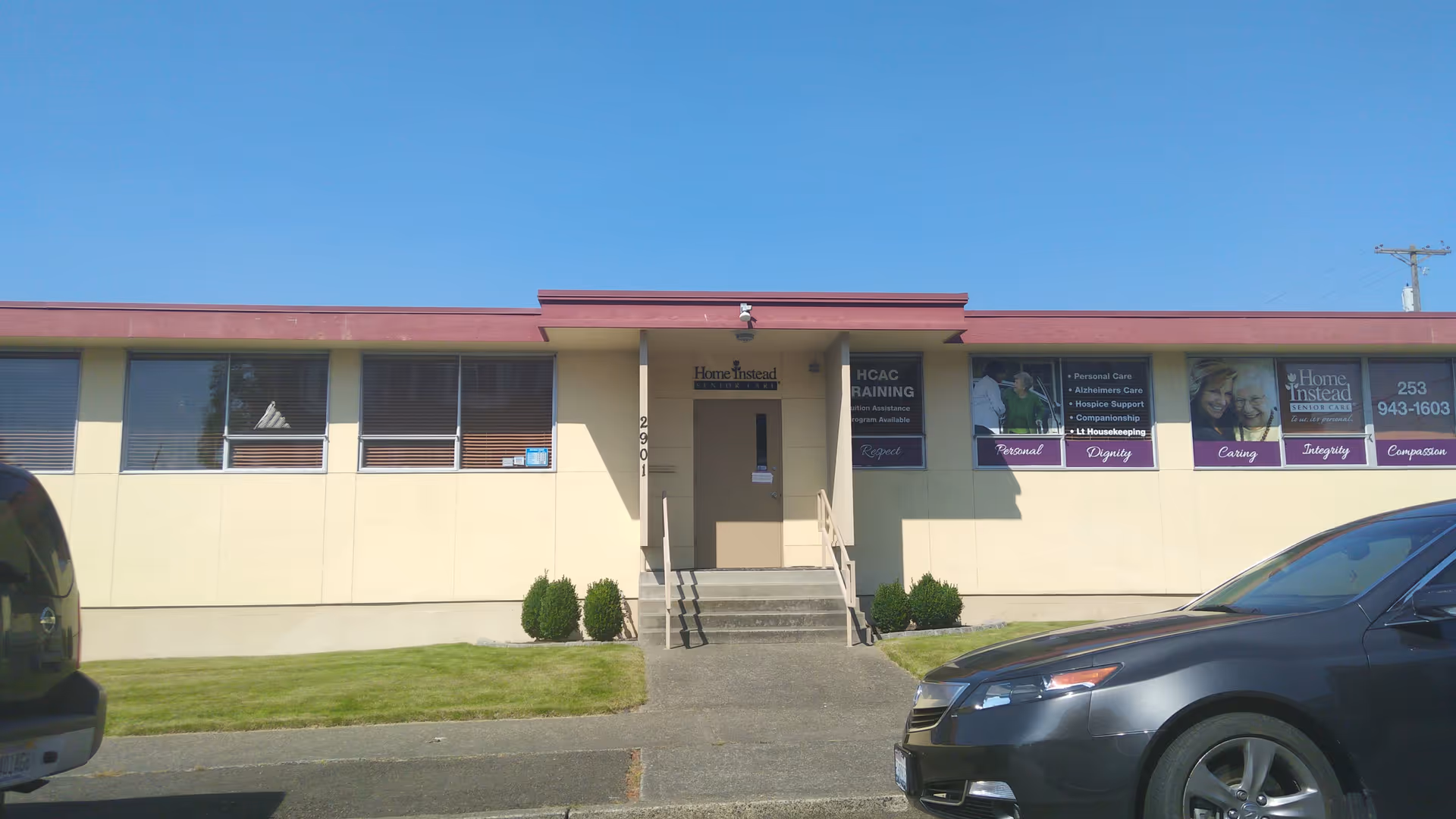 Exterior view of a single-story facility with a central entrance and banners along windows.