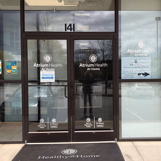 Glass entrance doors labeled Atrium Health At Home on the building front.