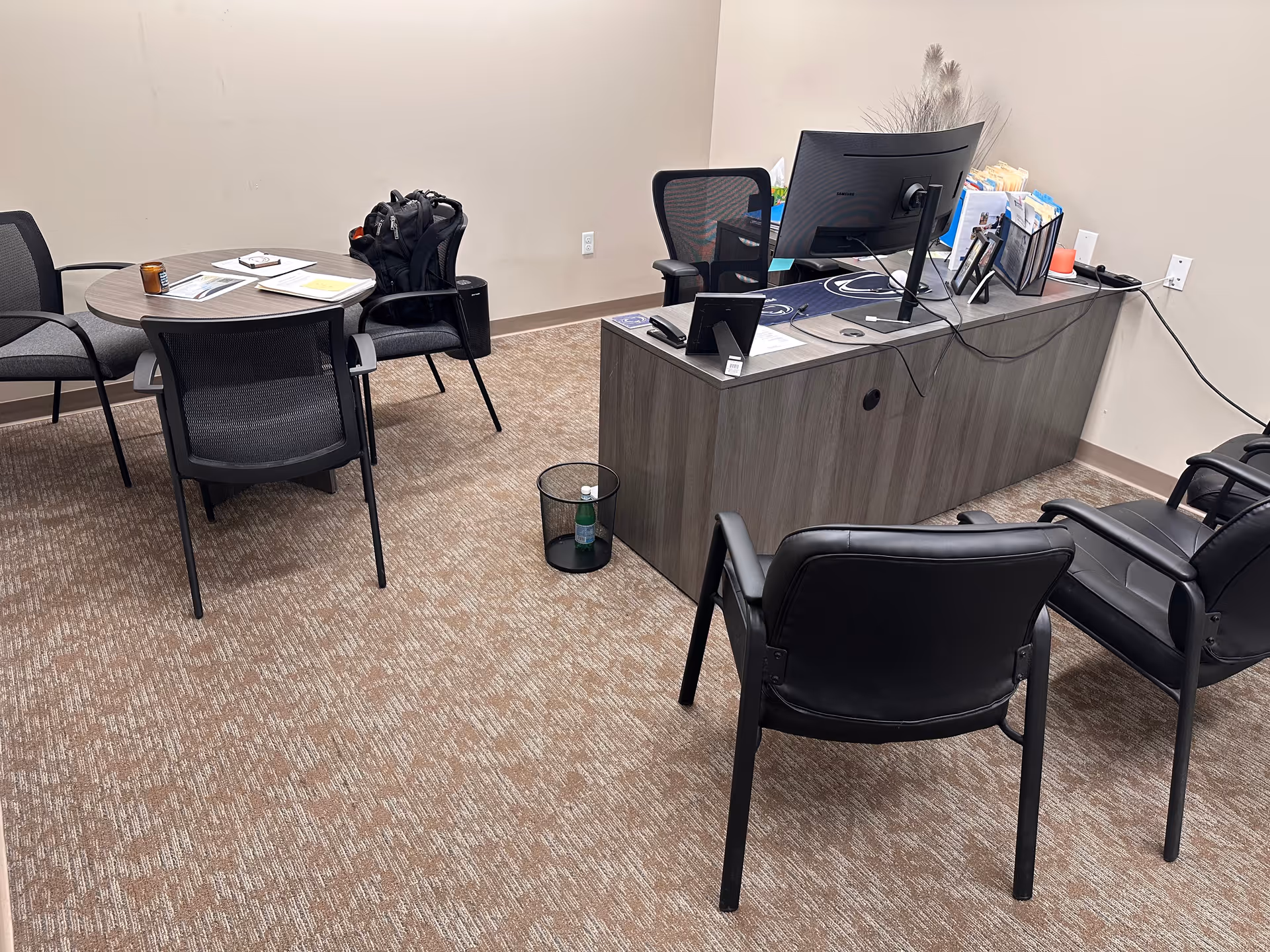 Interior office/reception area with a desk, computer, and round table with chairs.