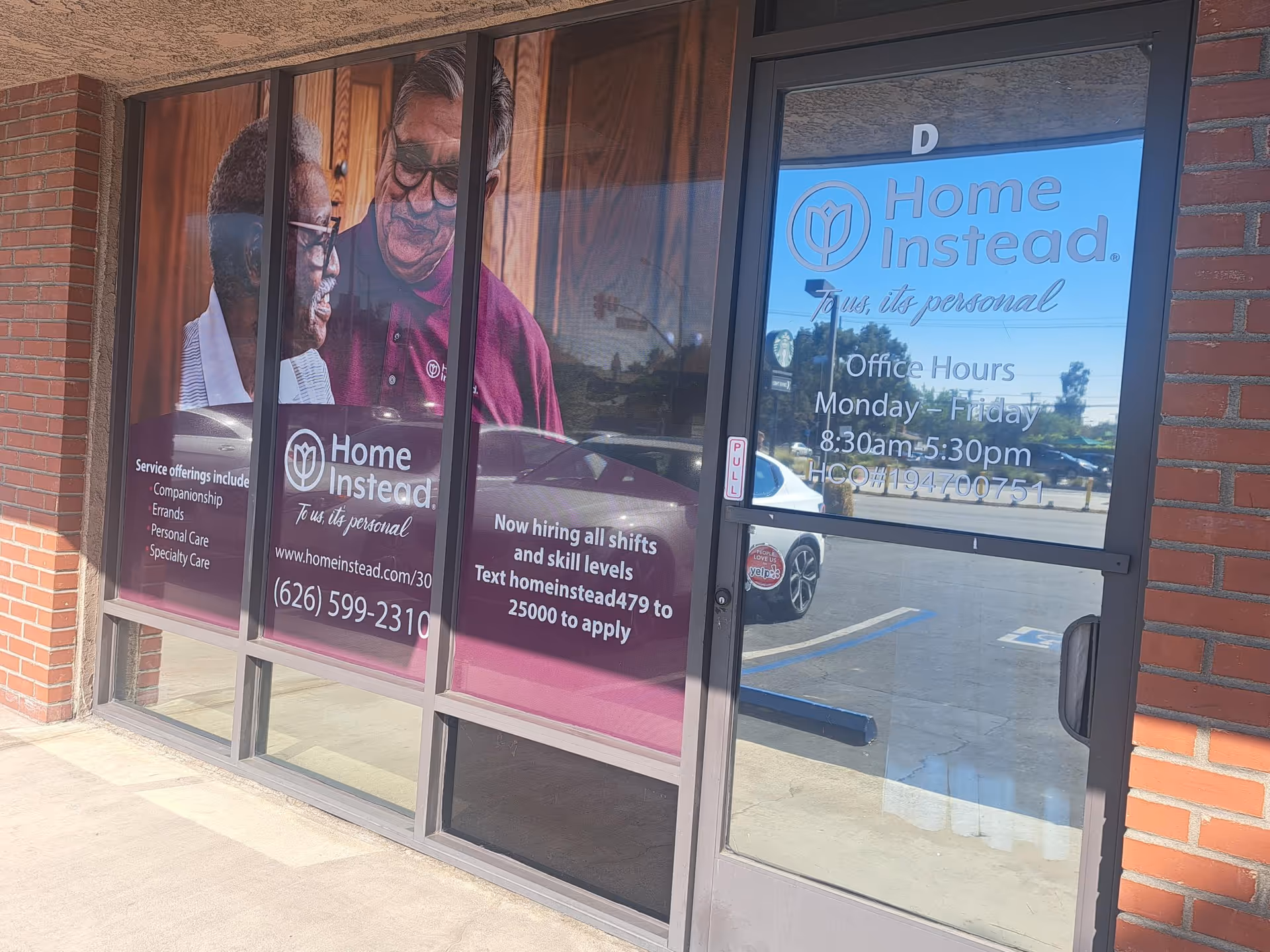 Home Instead facility entrance with branded glass windows and large promotional posters.