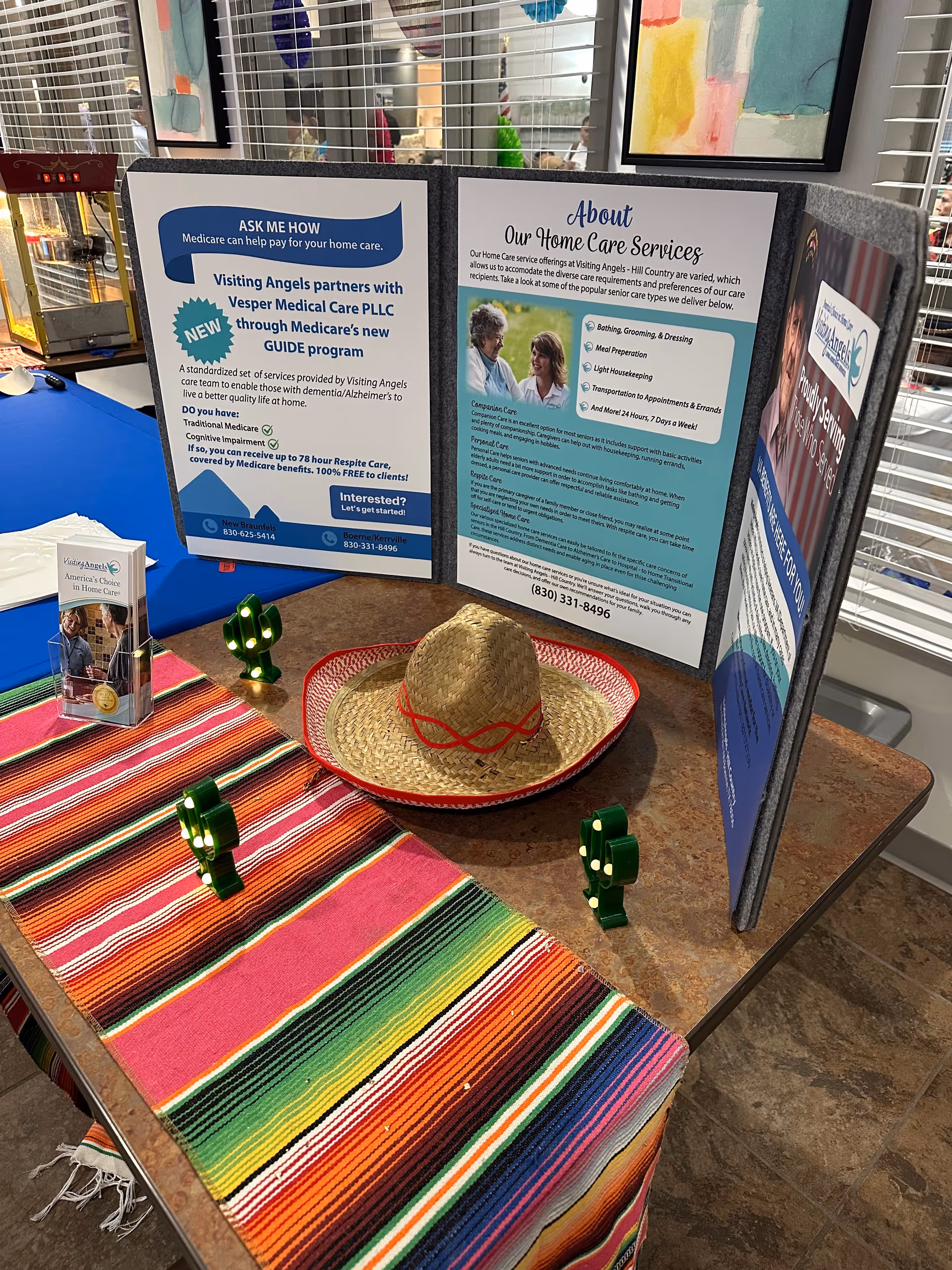A display table with informational posters, a sombrero, and colorful textile on a counter.