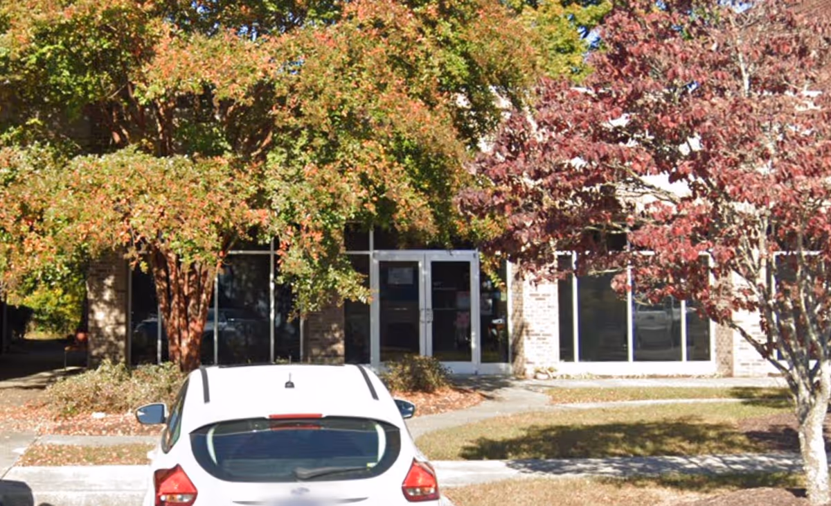Exterior view of a senior care facility with glass doors and a parked car.