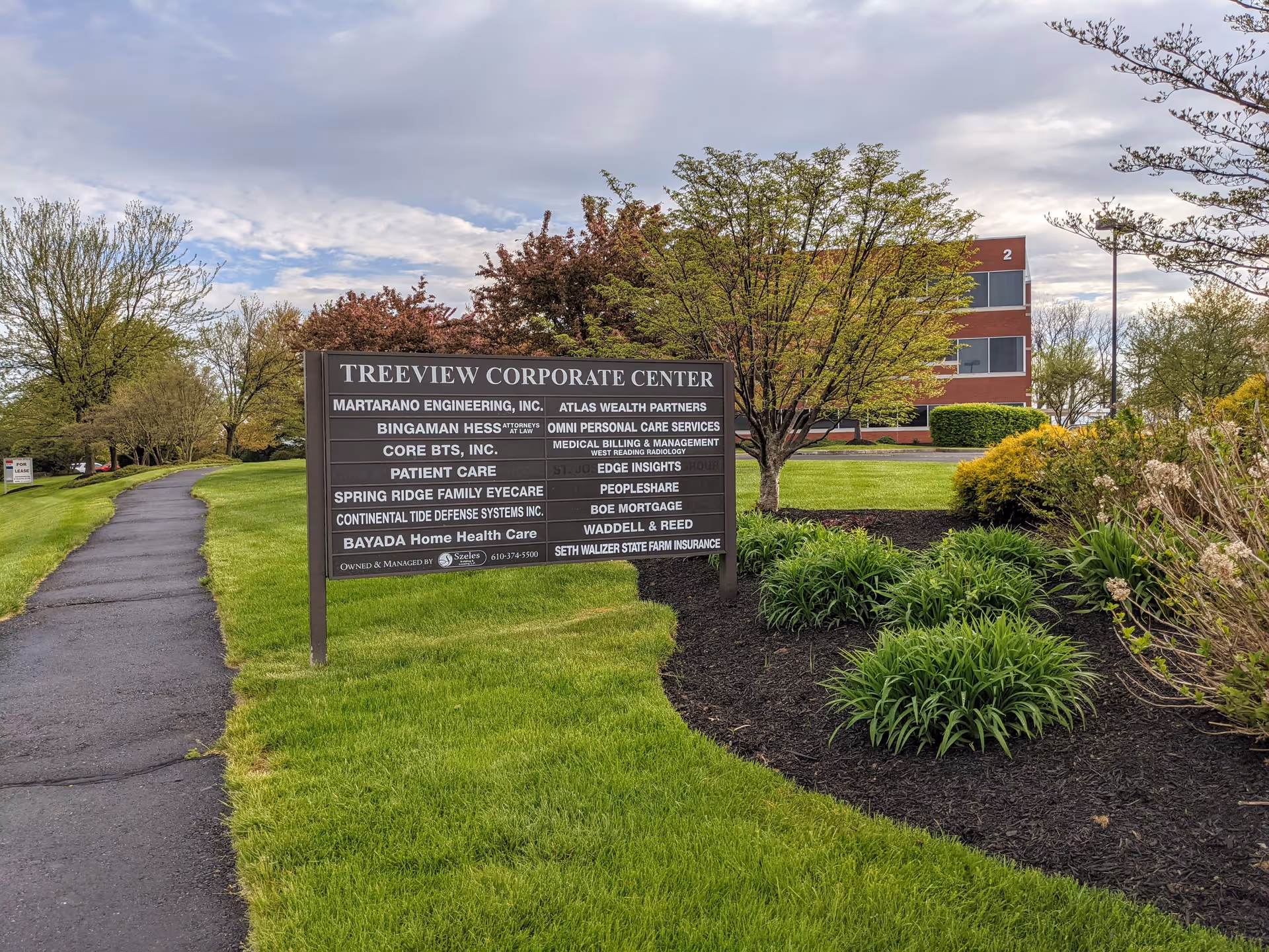 Outdoor view of Treeview Corporate Center sign in a landscaped area with a brick building behind.
