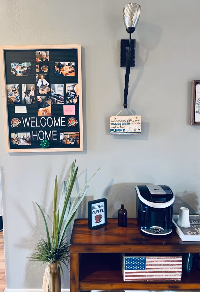 Interior wall featuring a Welcome Home collage, coffee station, plant, and Americana decor.