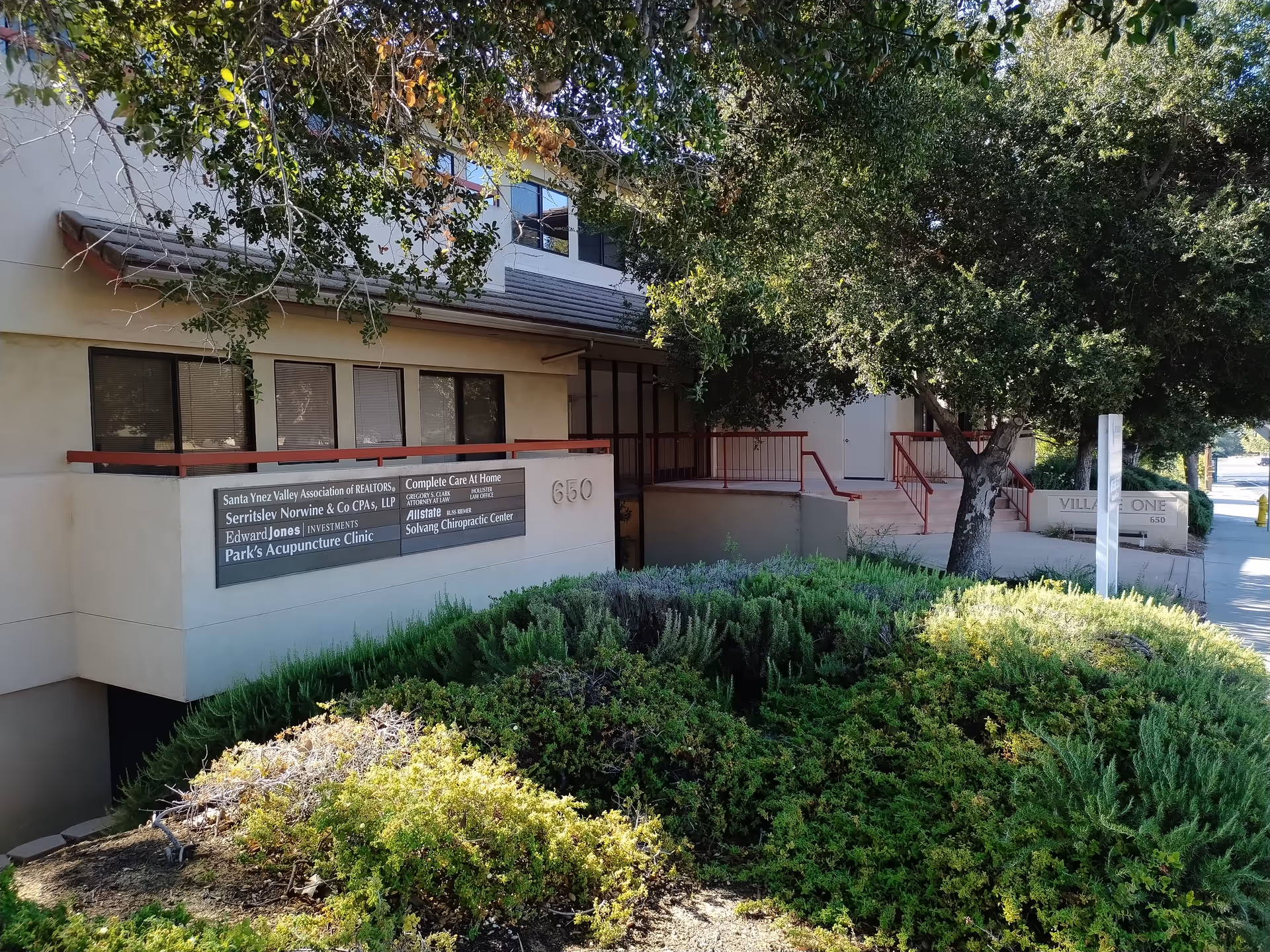 Exterior view of Complete Care at Home entrance with signs and shrubbery.