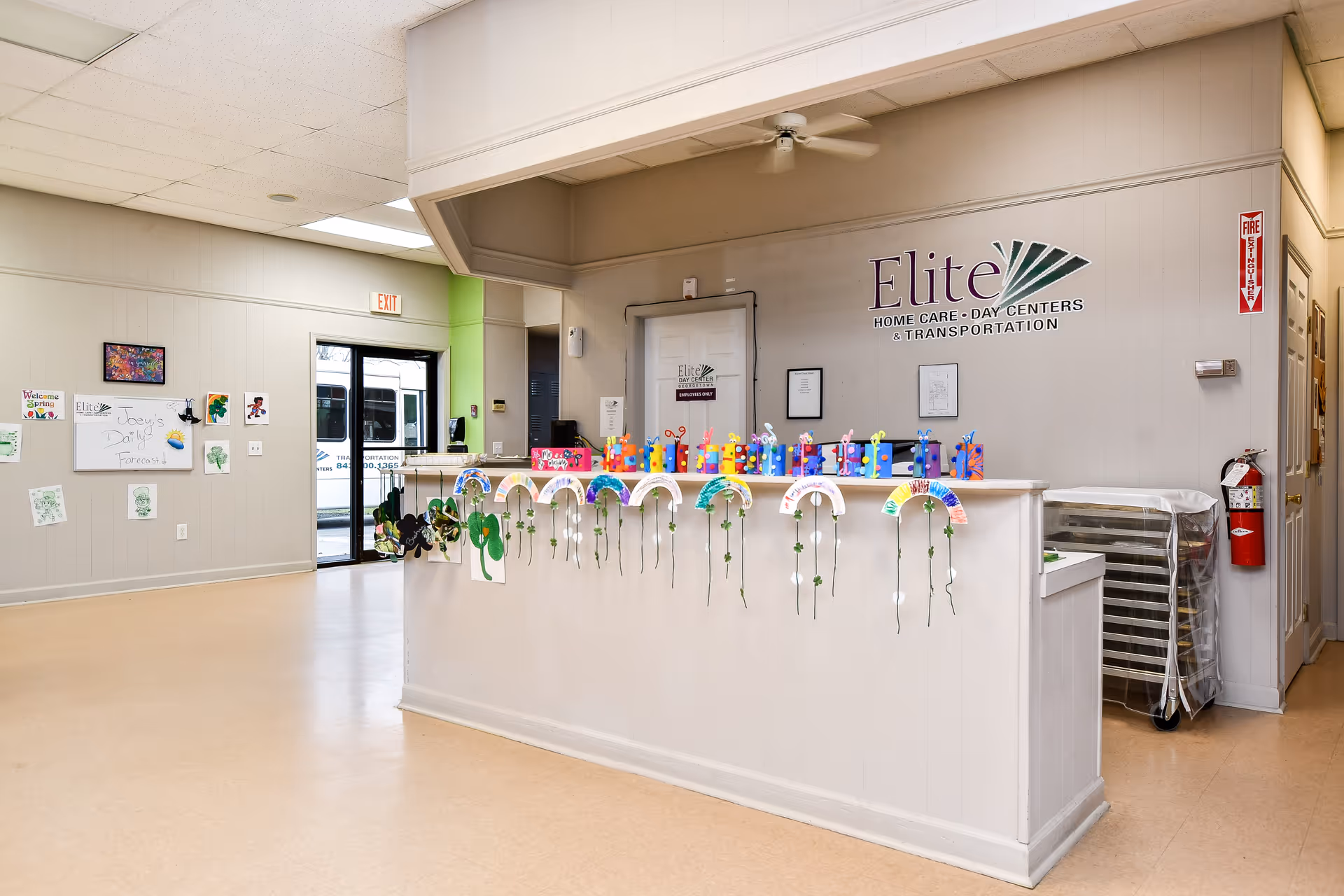 Reception area featuring a white front desk, crafts displayed along the edge, and Elite signage.