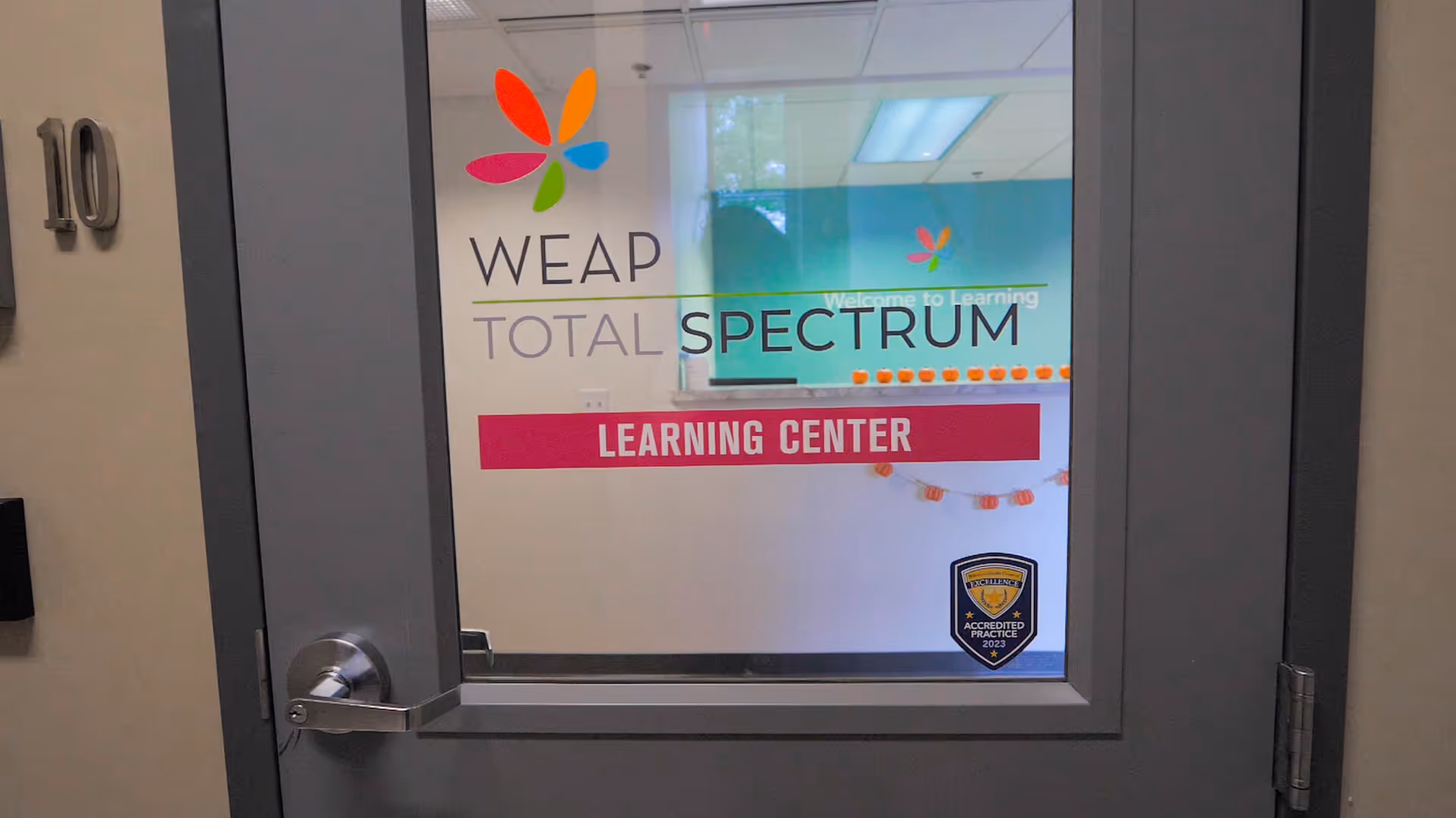 Glass door with WEAP TOTAL SPECTRUM LEARNING CENTER signage inside a building