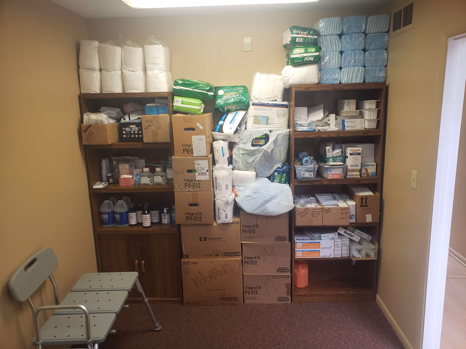 Storage room with stacked boxes and medical supplies on shelves.