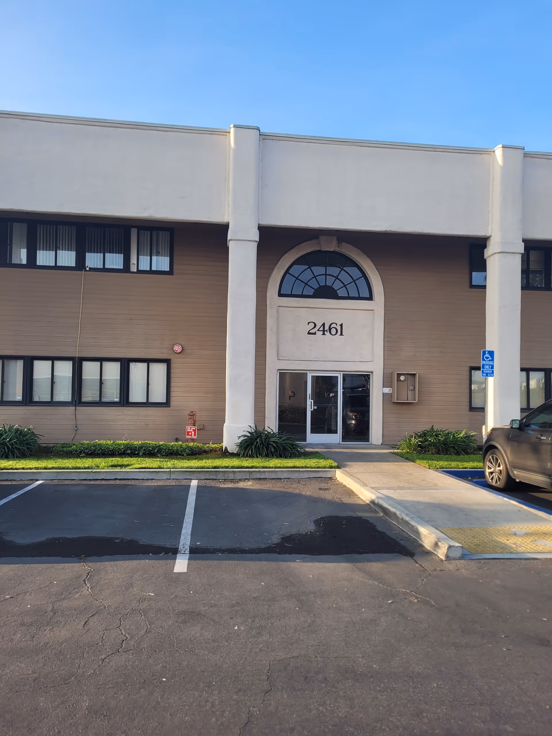 Front view of a senior living facility entrance with address 2461 and parking lot