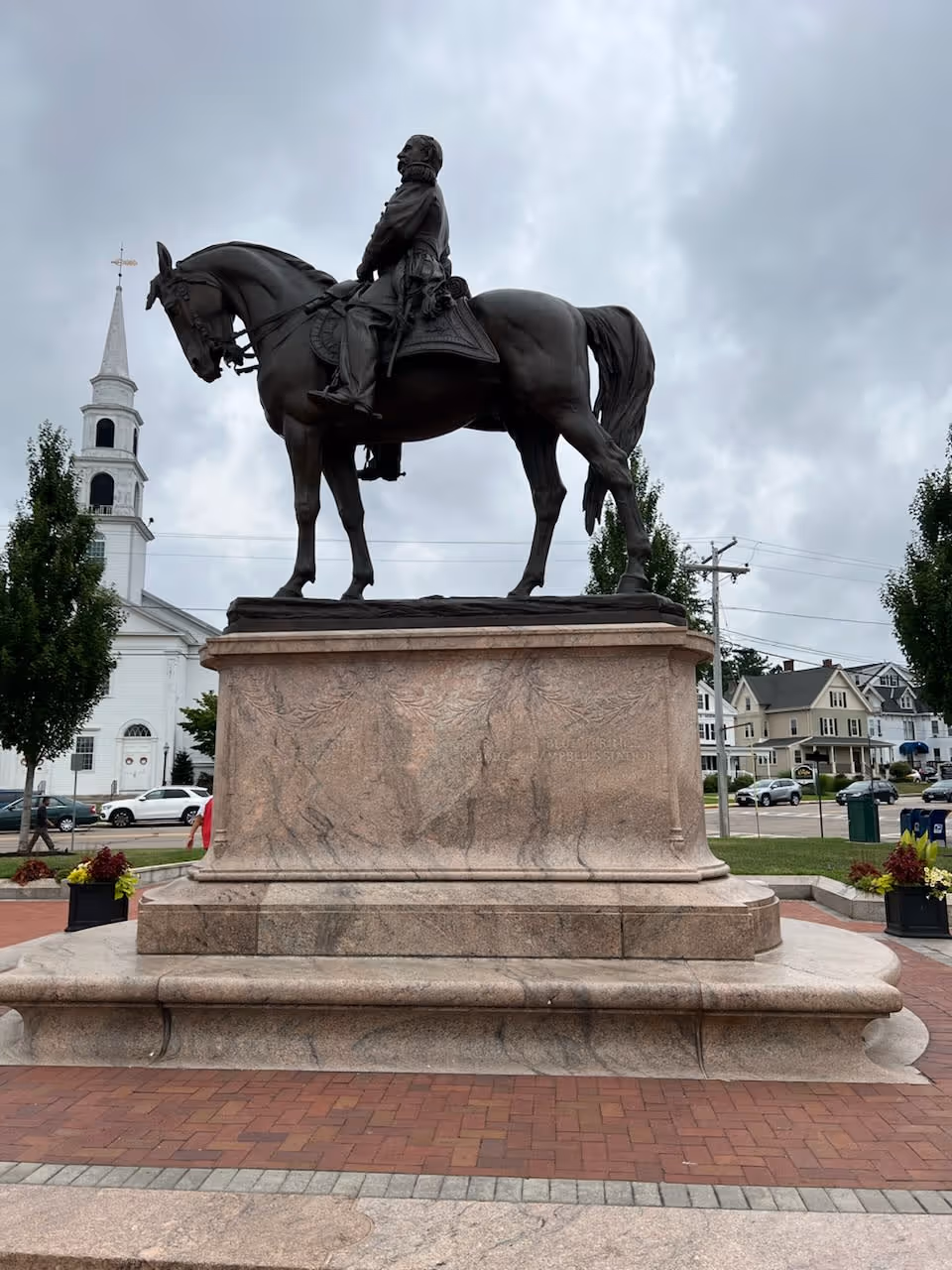 Equestrian statue on a stone pedestal in a town square with a church nearby.