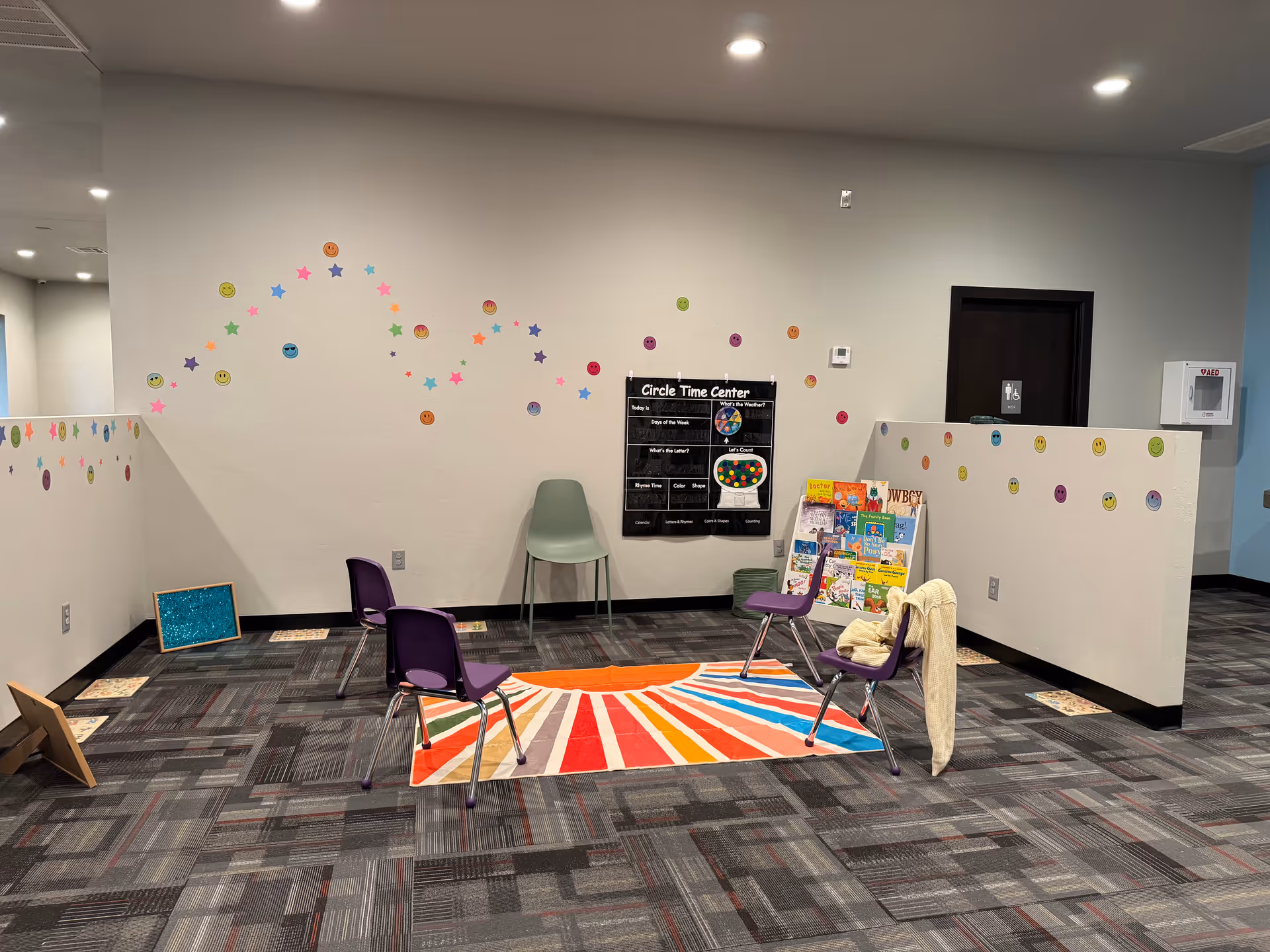 Therapy activity area with circular chair arrangement around a colorful rug in a bright room
