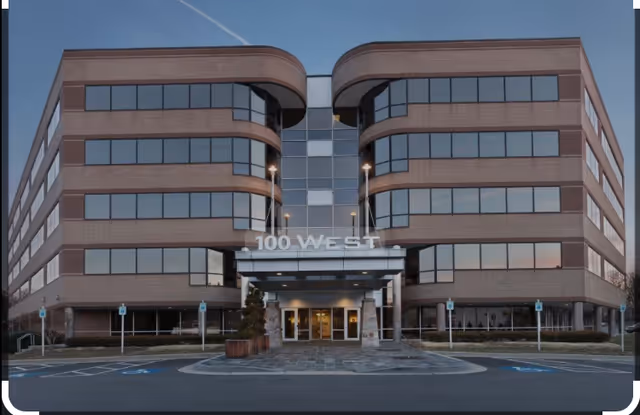 Exterior view of a modern brick senior living building with a central entrance labeled 100 West.