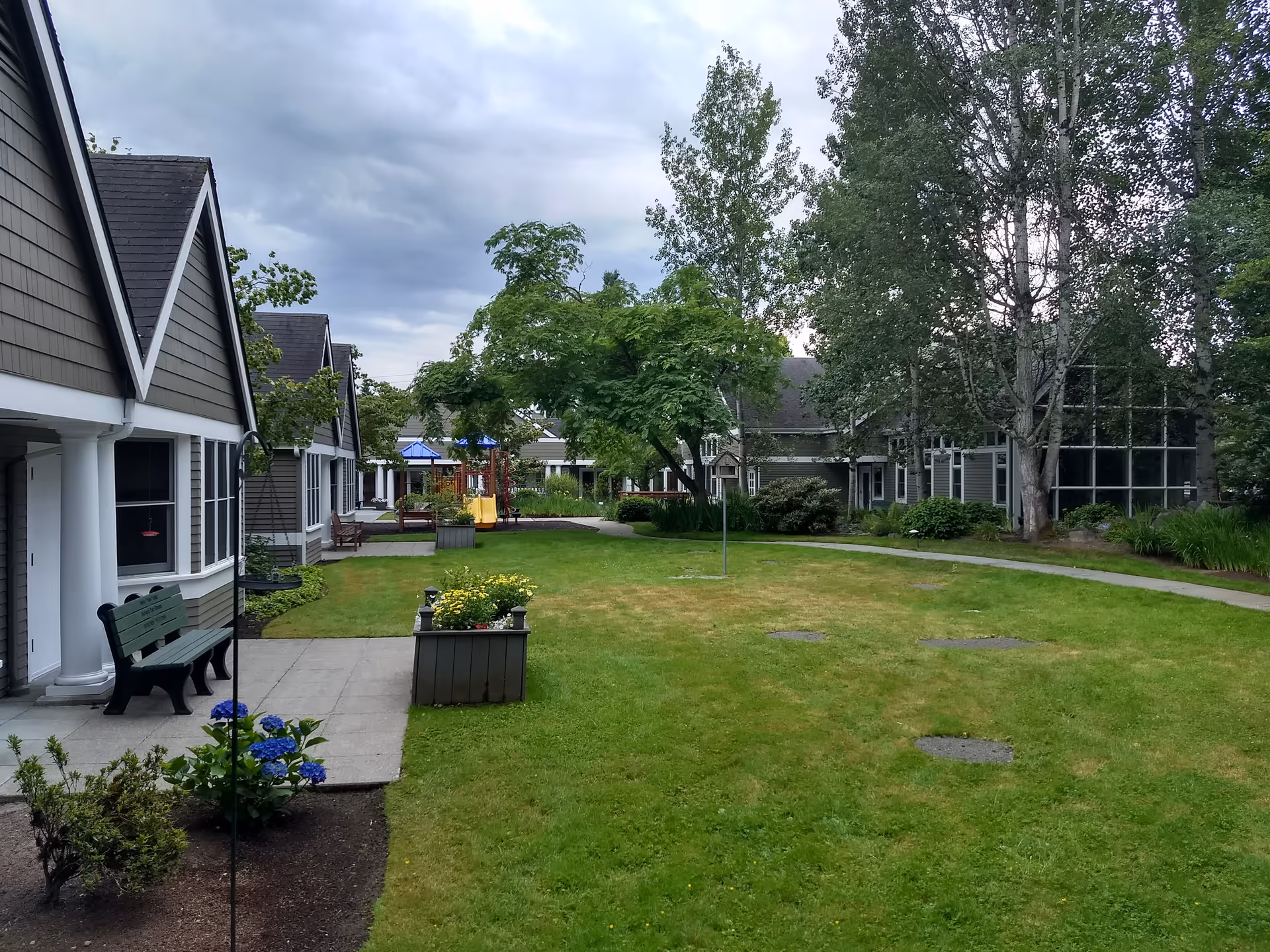 Outdoor courtyard at EvergreenHealth Hospice Services with benches, planters, and trees.