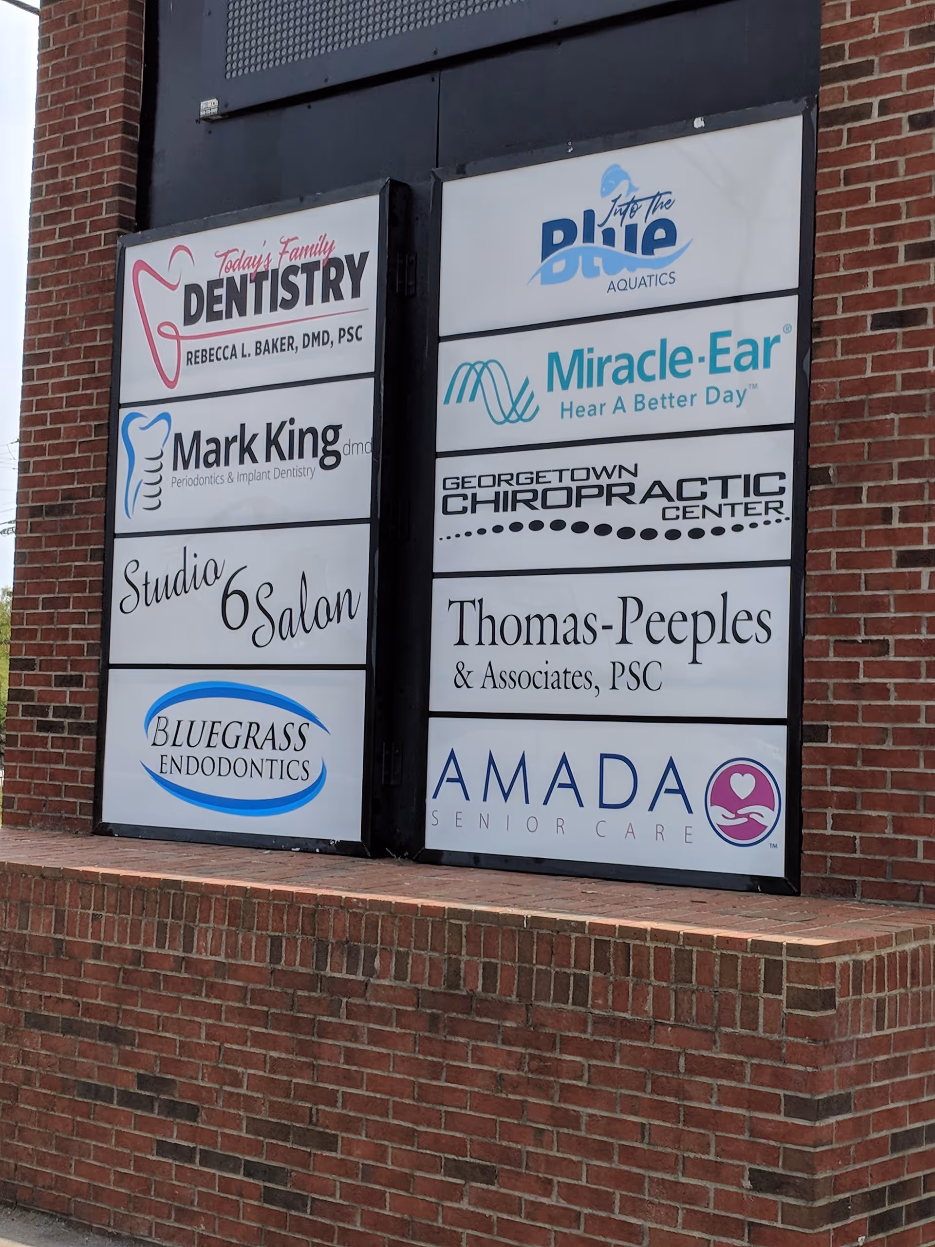 Brick exterior with multi-panel signs displaying Amada Senior Care and other logos.