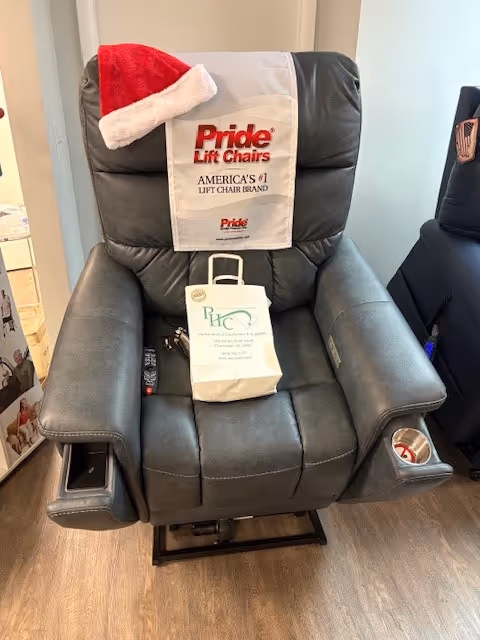 A dark leather lift chair in a senior living room with PHC bag and Santa hat.