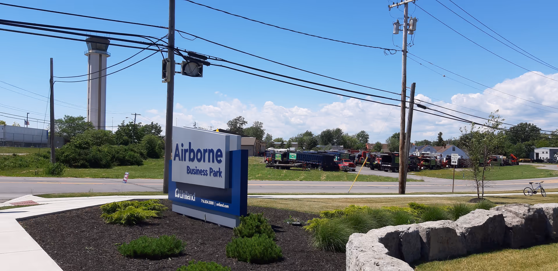 Outdoor street scene with a blue Airborne Business Park sign and parked trucks.