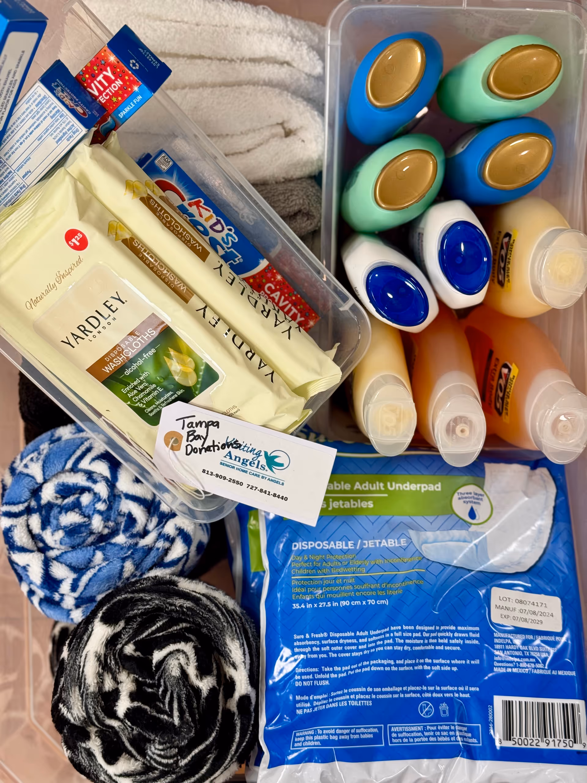 Assorted care supplies and towels in a plastic bin labeled Visiting Angels.