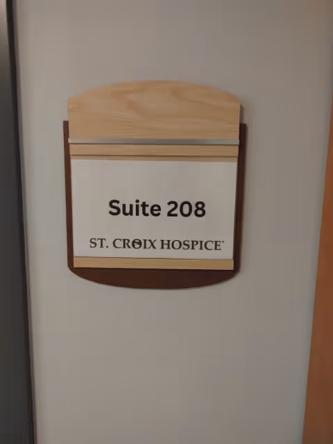 Wall-mounted plaque displays Suite 208 and St. Croix Hospice on a hallway wall.