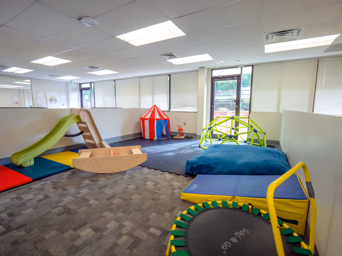 Indoor playroom with colorful foam mats, a slide, tent, and climbing structures.