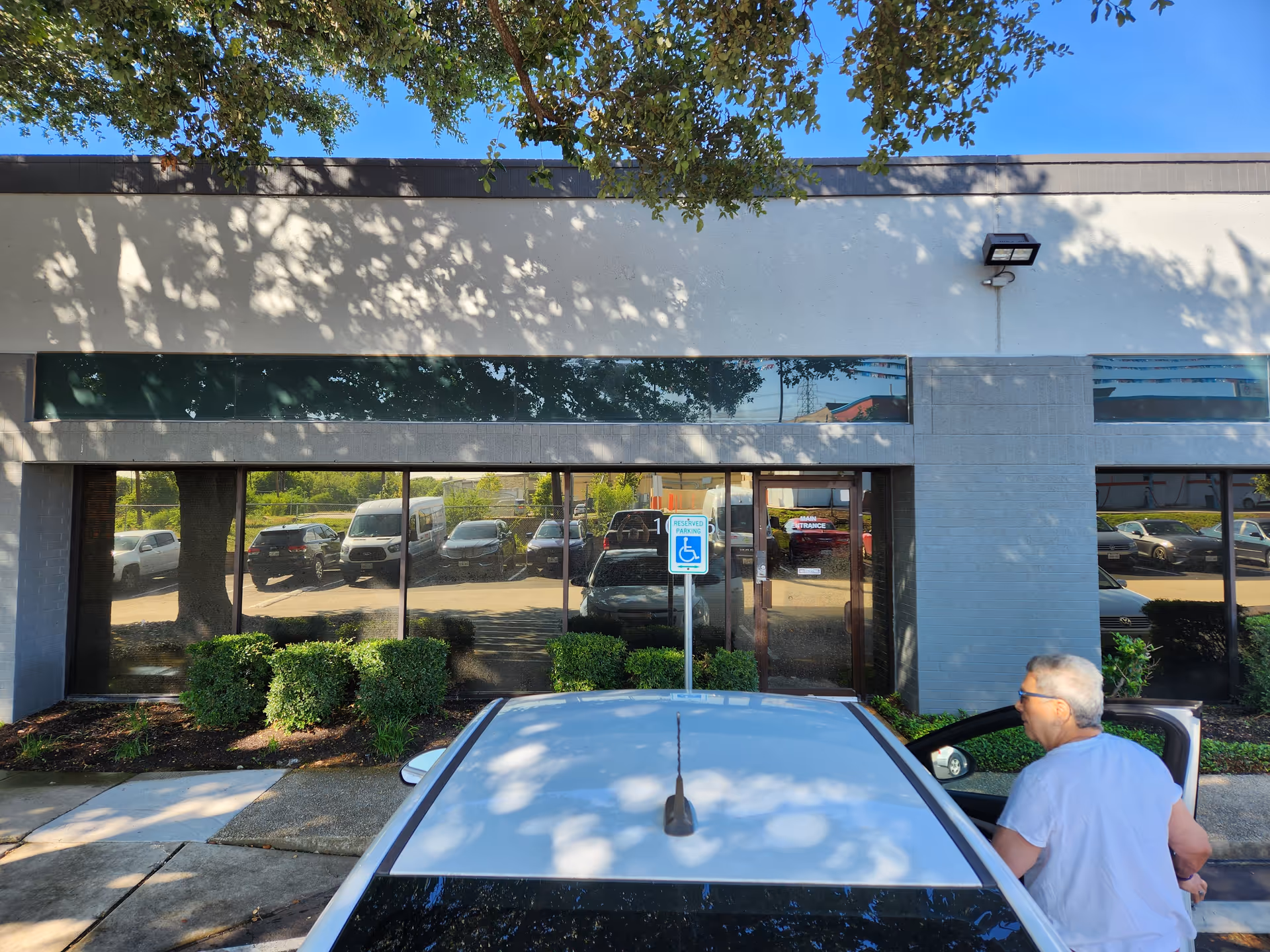Front exterior of a senior living facility with parked cars and a man near a vehicle.