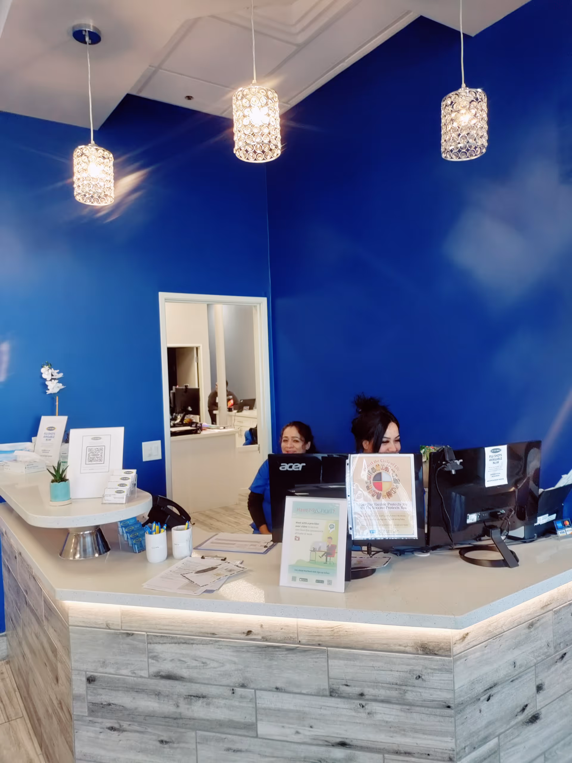 Blue lobby reception with two staff at computers behind a curved counter.