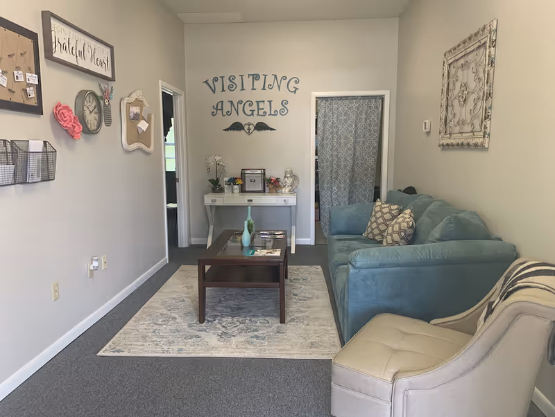 Cozy living room lounge with teal sofa, coffee table, rug, and wall decor.