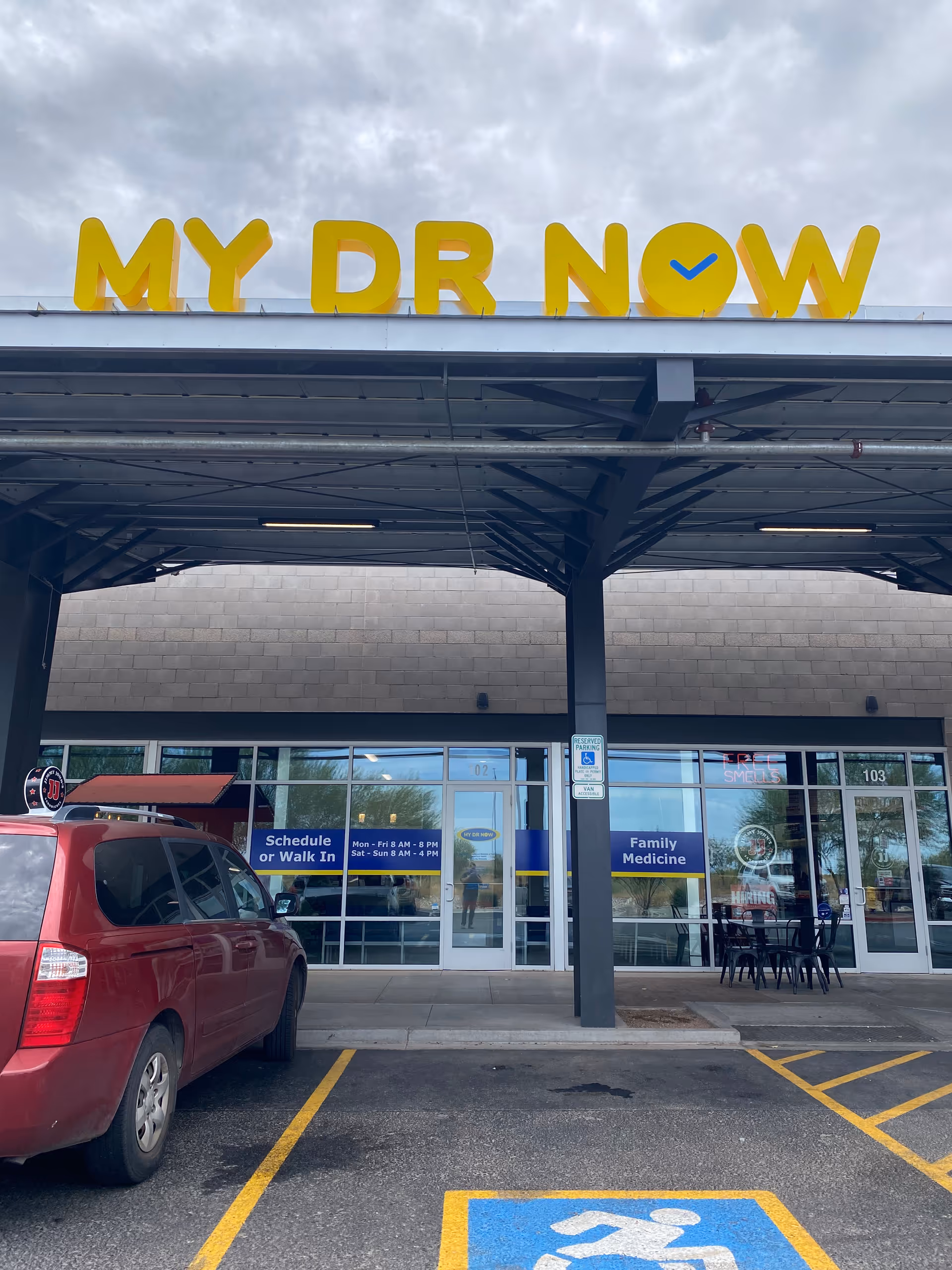 Exterior view of a MY DR NOW clinic storefront with glass doors and parking.