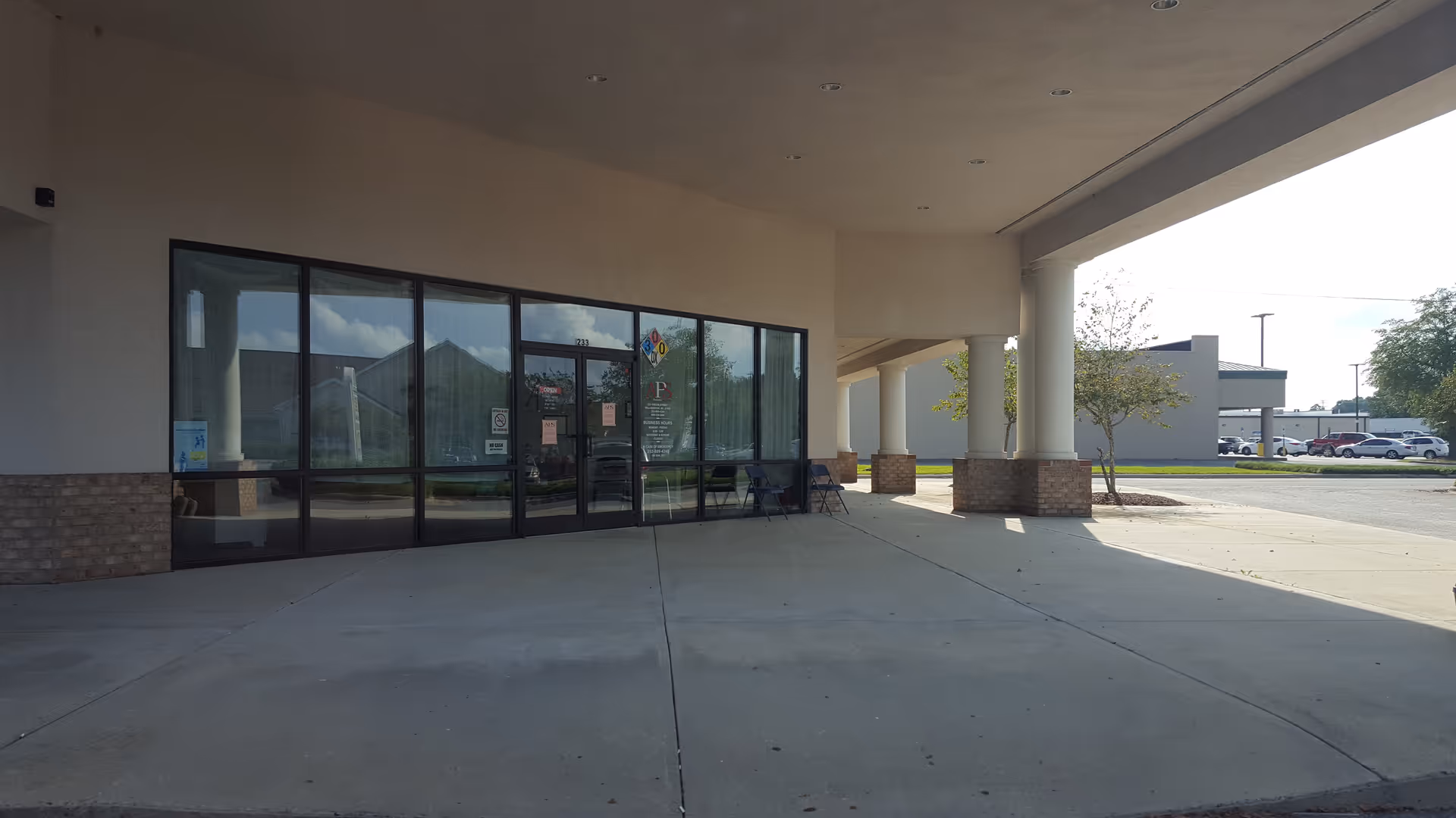 Exterior view of a facility entrance with glass doors under a covered walkway.